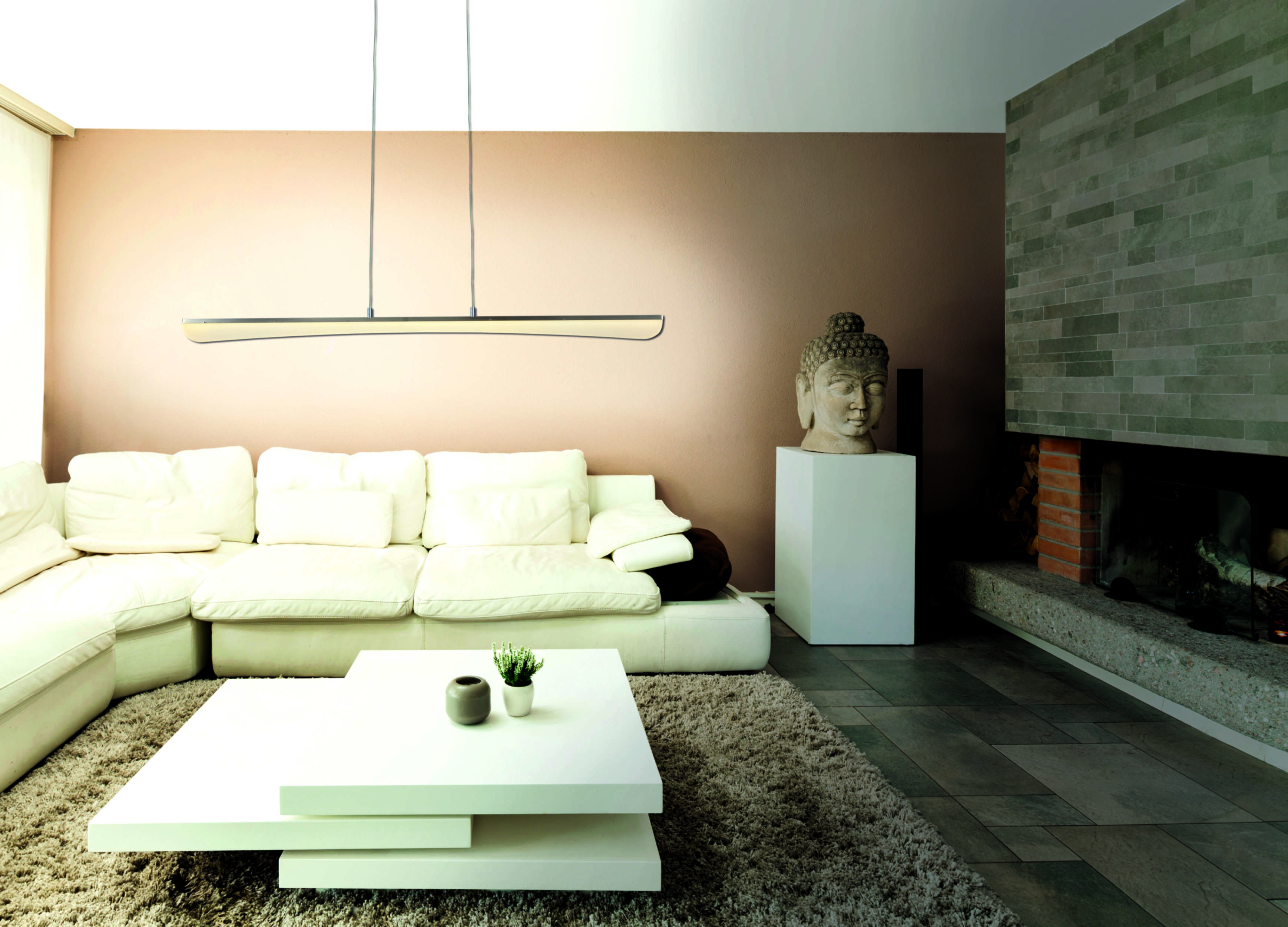 Weißes Wohnzimmer mit weißem Sofa, Couchtisch und einer Buddha-Kopf-Skulptur auf einem Sockel.
