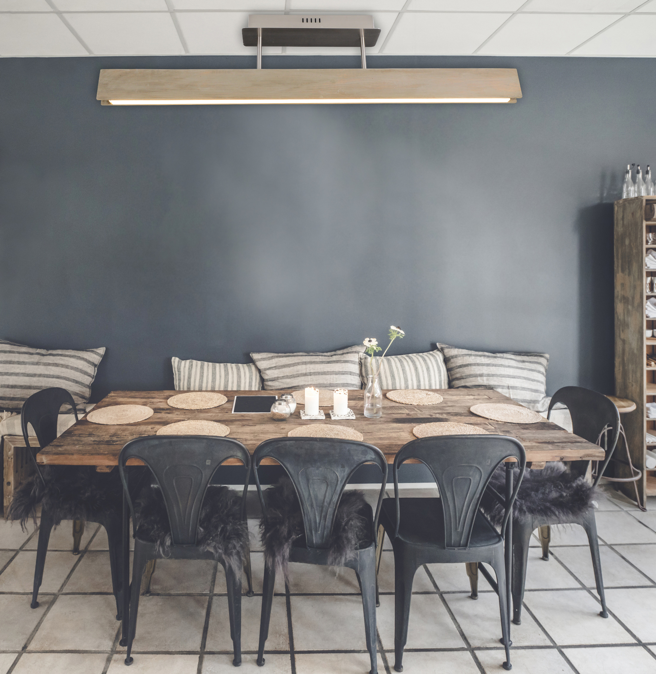 Ein Esszimmer mit einem langen Holztisch, schwarzen Stühlen und einer dunkelblauen Wand.