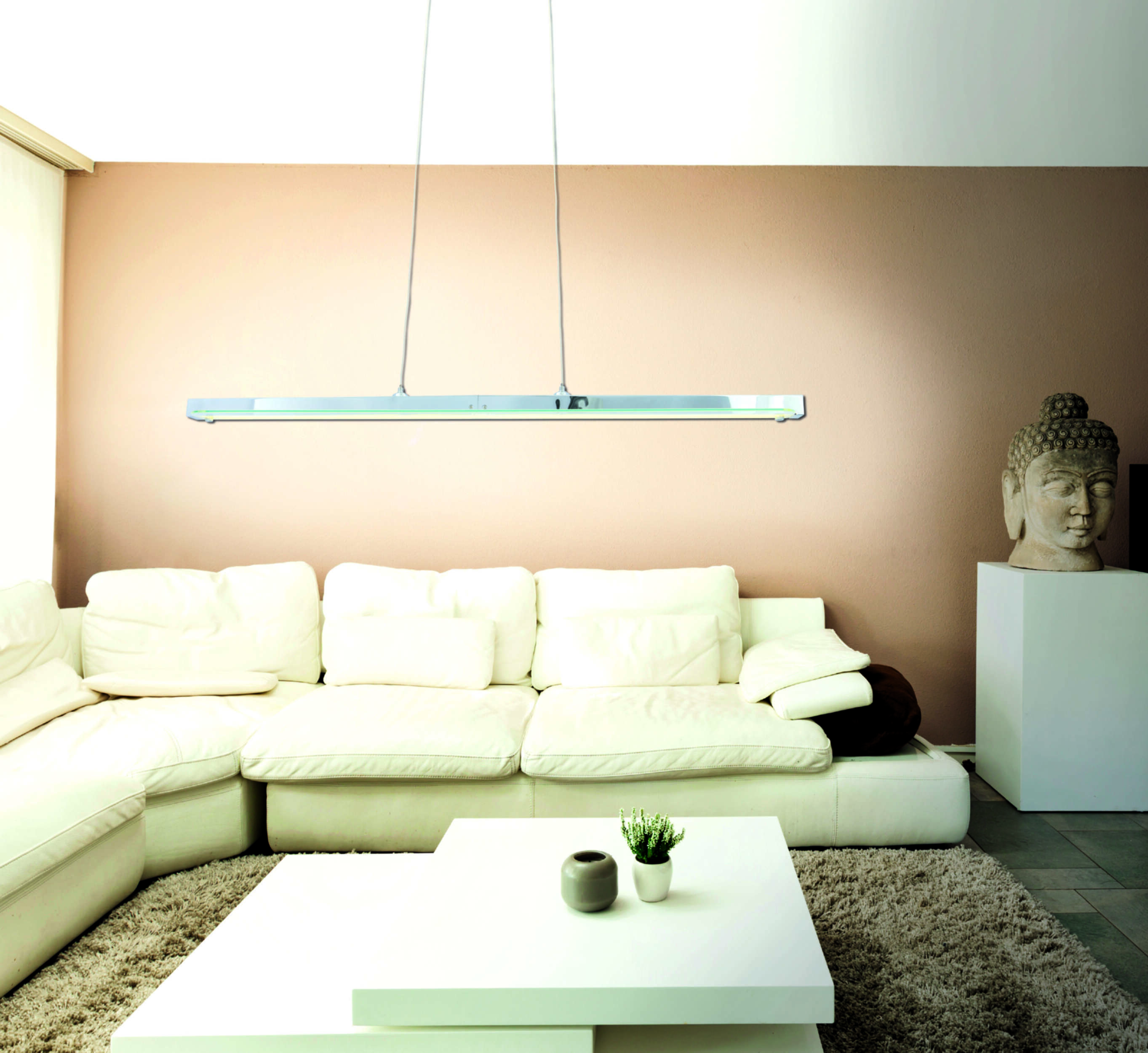 Ein modernes Wohnzimmer mit weißem Sofa, Couchtisch und einer Hängeleuchte.