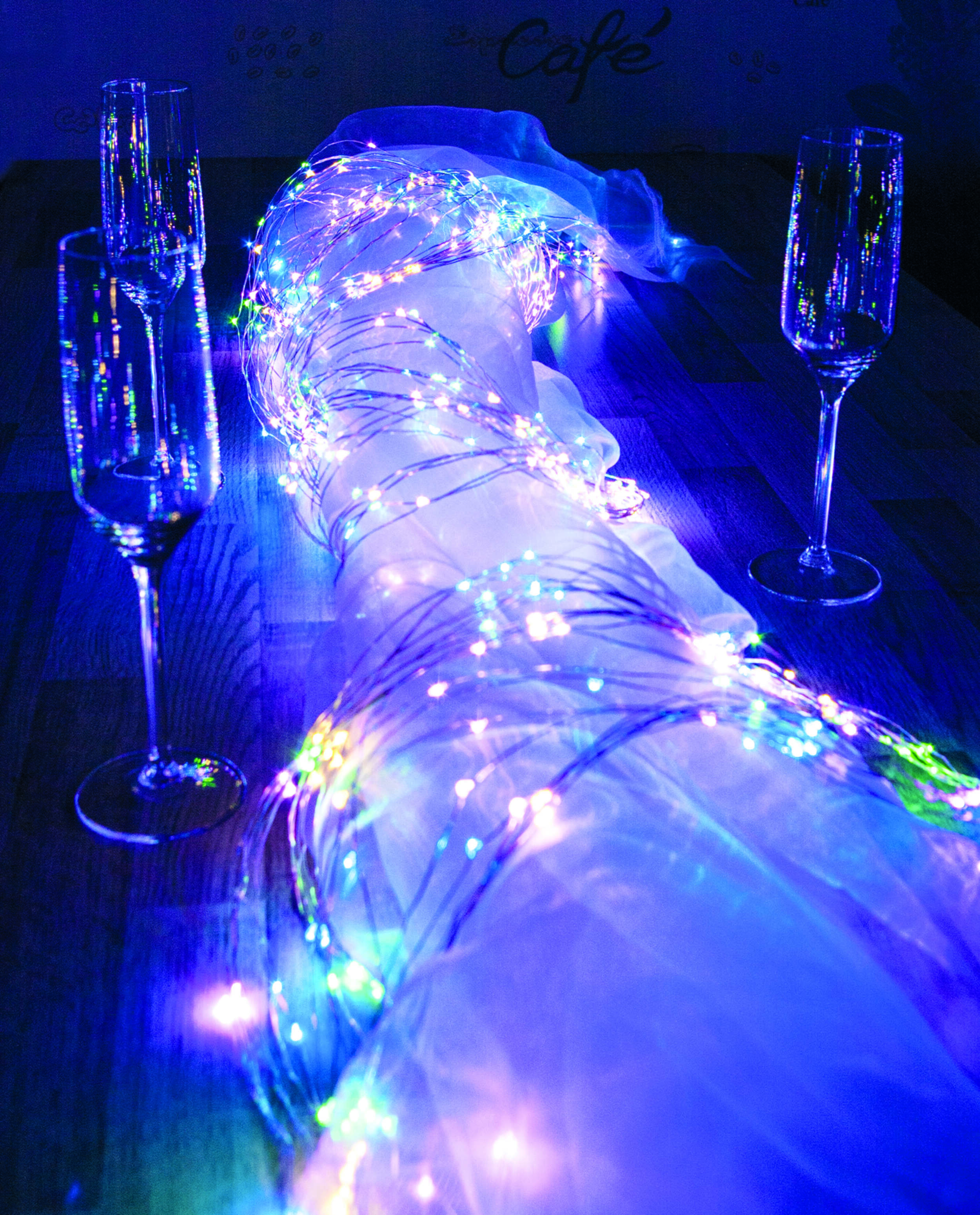 Champagnergläser und Lichterketten auf einem Tisch. Der Hintergrund ist dunkel.