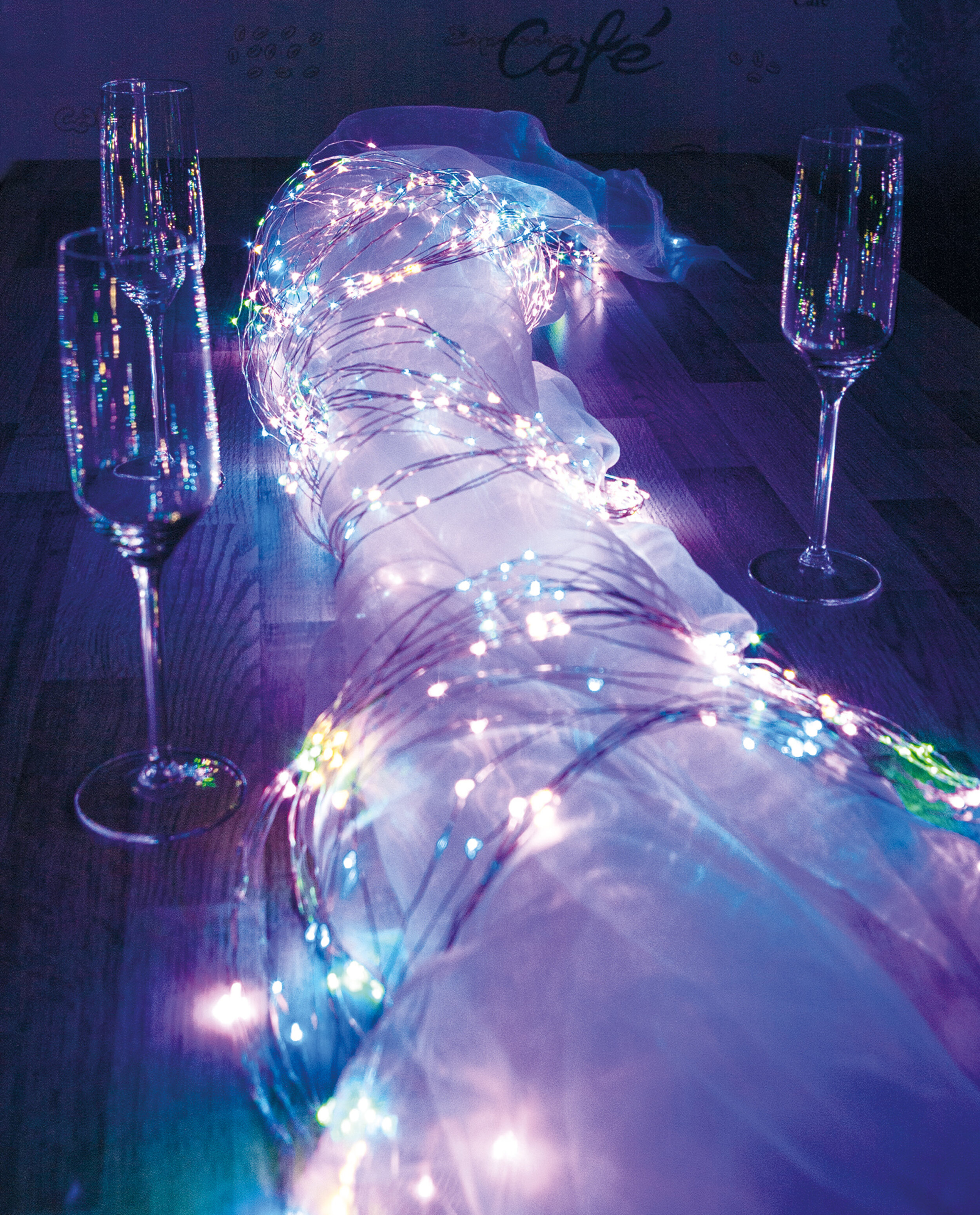 Champagnergläser und Lichterketten auf einem Tisch. Der Hintergrund ist dunkel.
