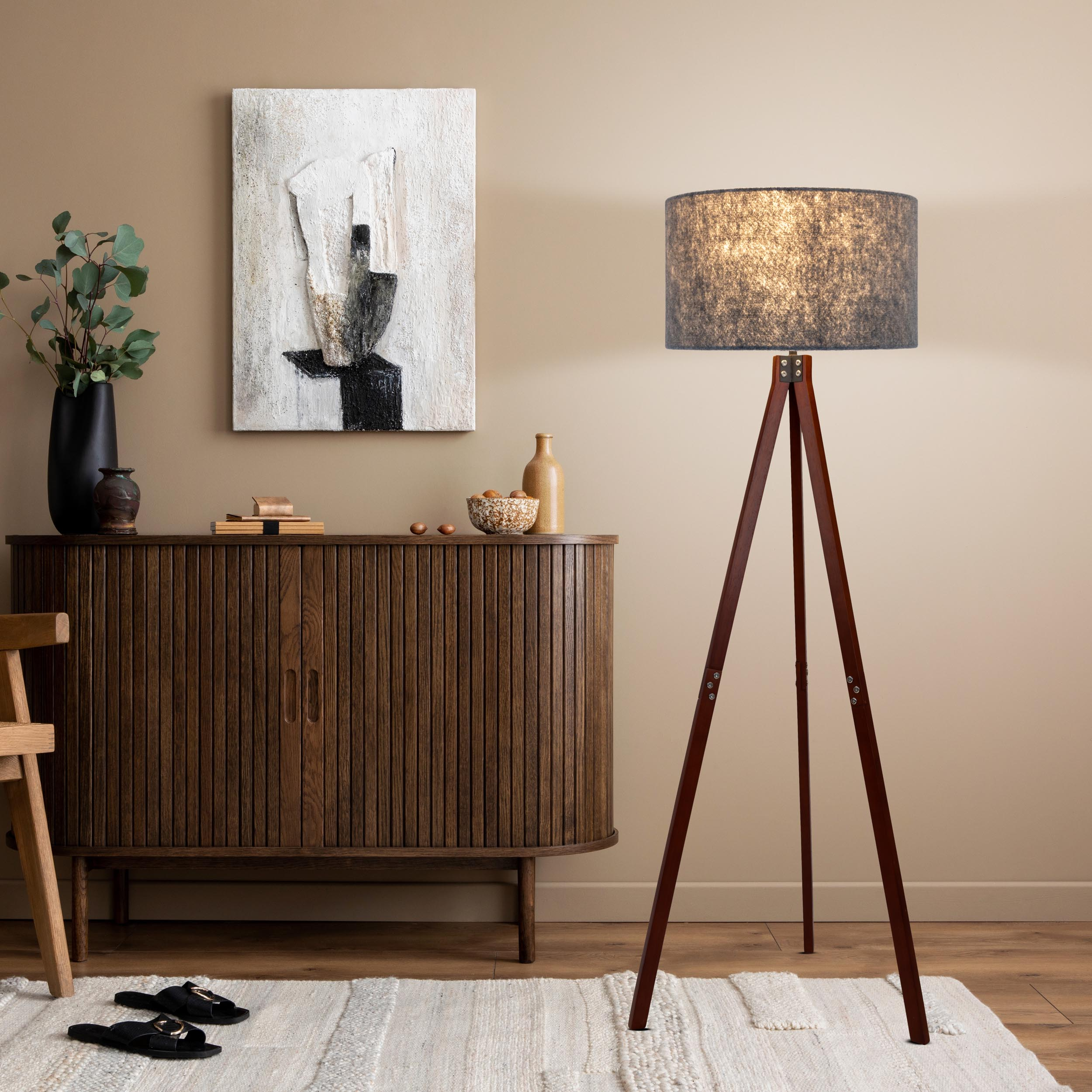 Wohnzimmer-Setup mit Stehlampe, Kunst, Schrank und Dekorationsartikeln.