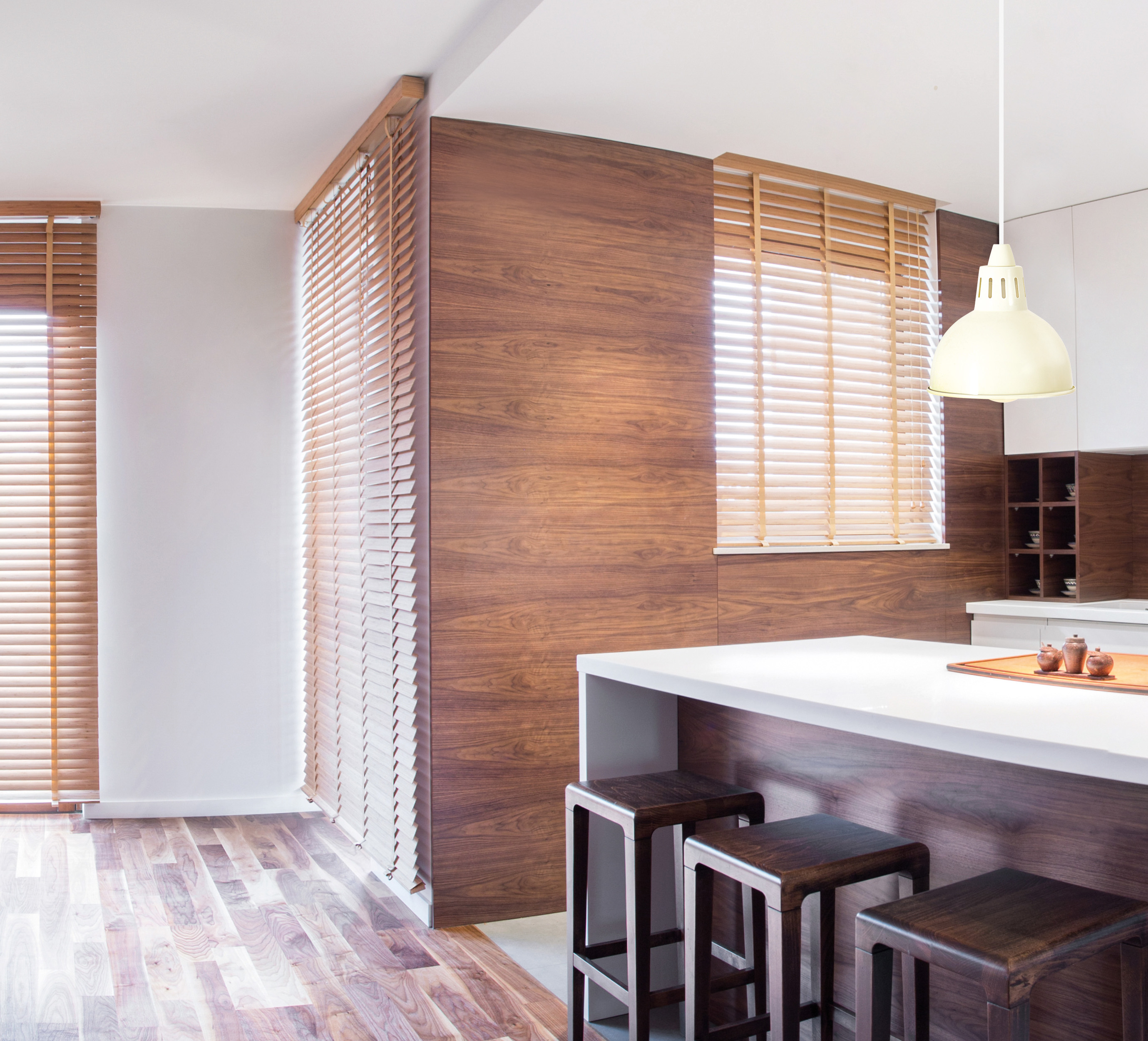 Modernes Kücheninterieur mit Holzverkleidung, Holzjalousien und weißer Arbeitsplatte.
