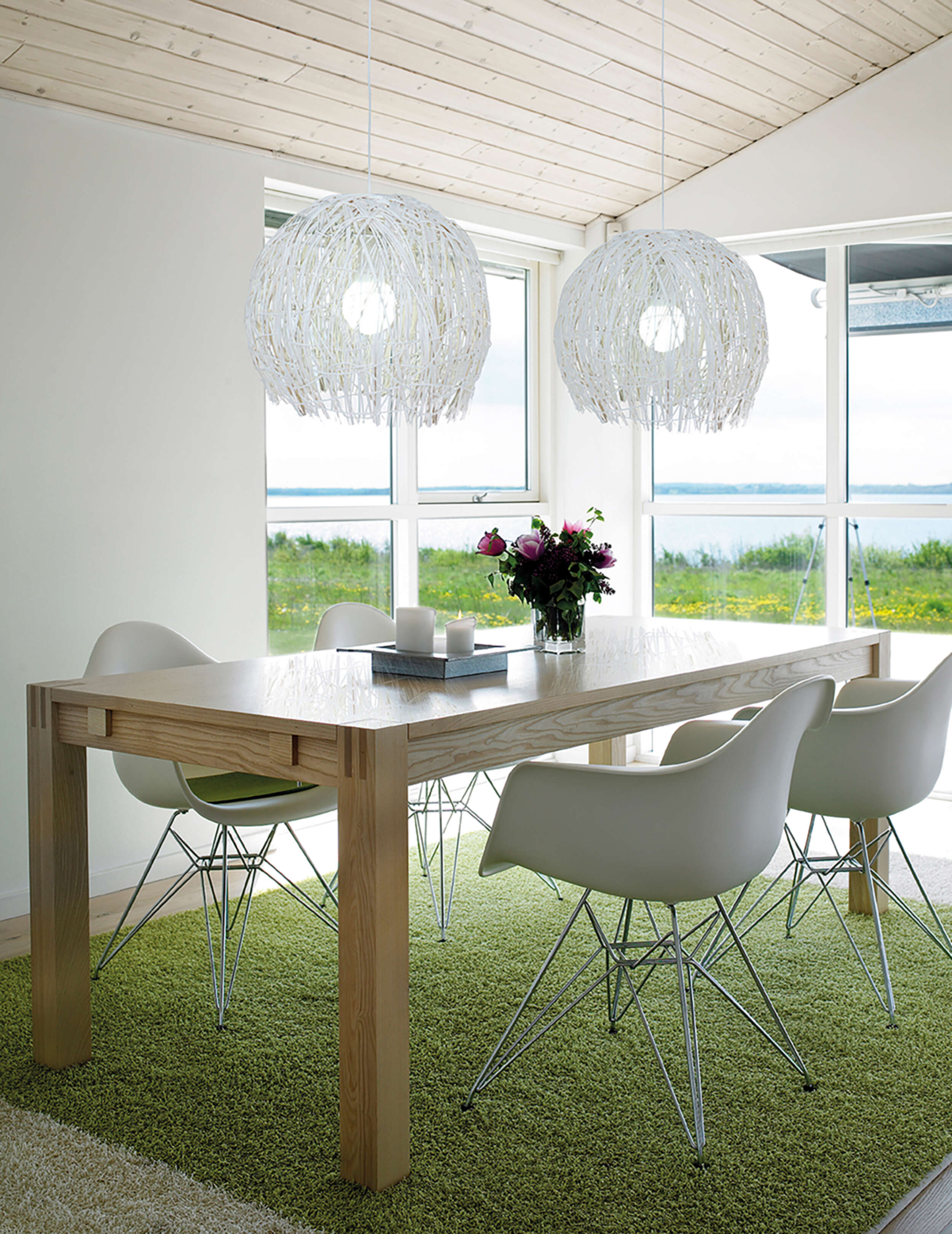 Ein Esszimmer mit Holztisch, weißen Stühlen und Pendelleuchten.
