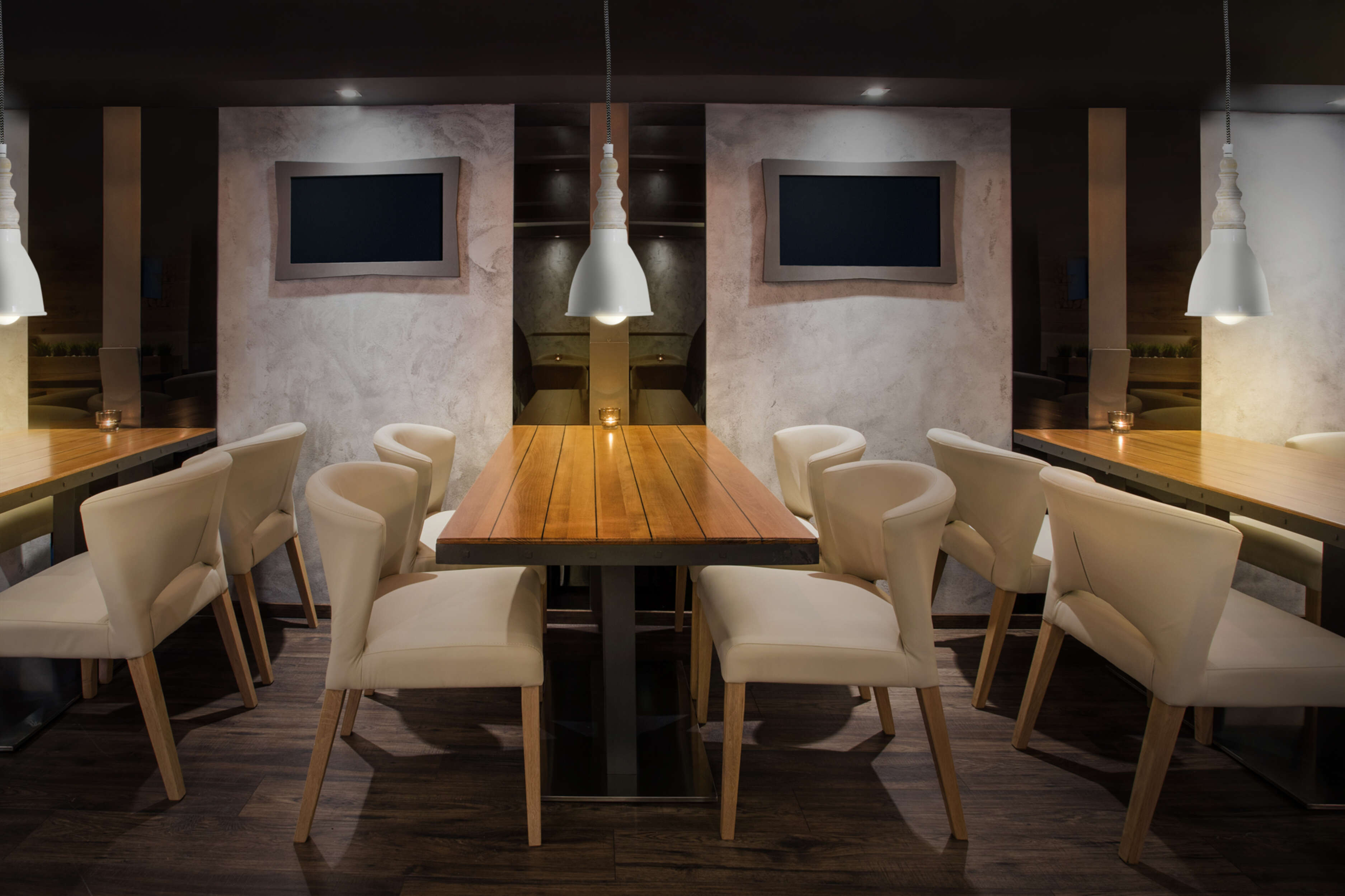 Ein Restaurantinnenraum mit Tischen und Stühlen. Lichter hängen von der Decke.
