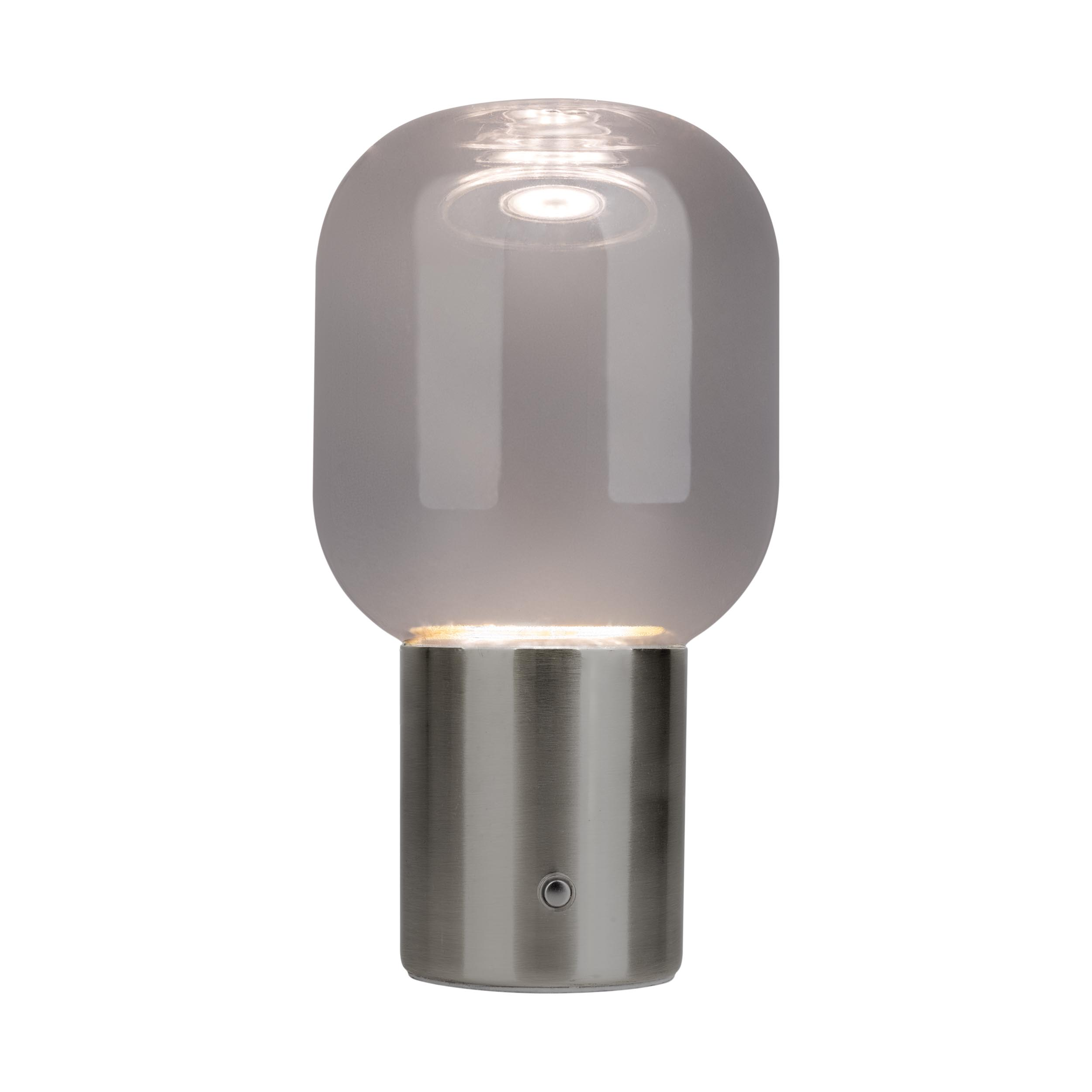 Eine moderne Tischlampe mit rundem Glasaufsatz und metallischem Sockel. Die Lampe ist eingeschaltet.