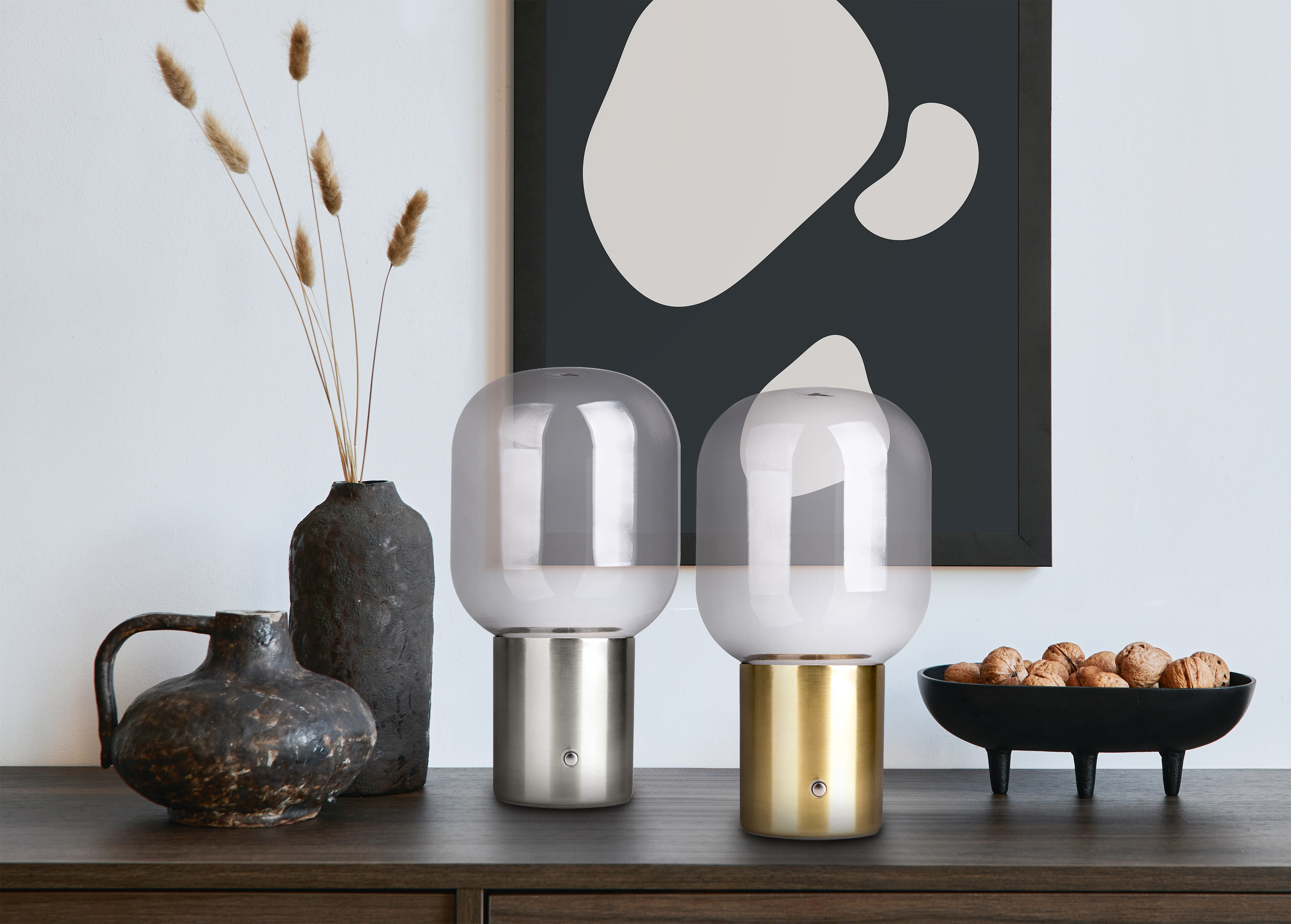 Zwei Tischlampen mit Glasschirmen und eine Vase mit Trockenblumen auf einem Tisch.