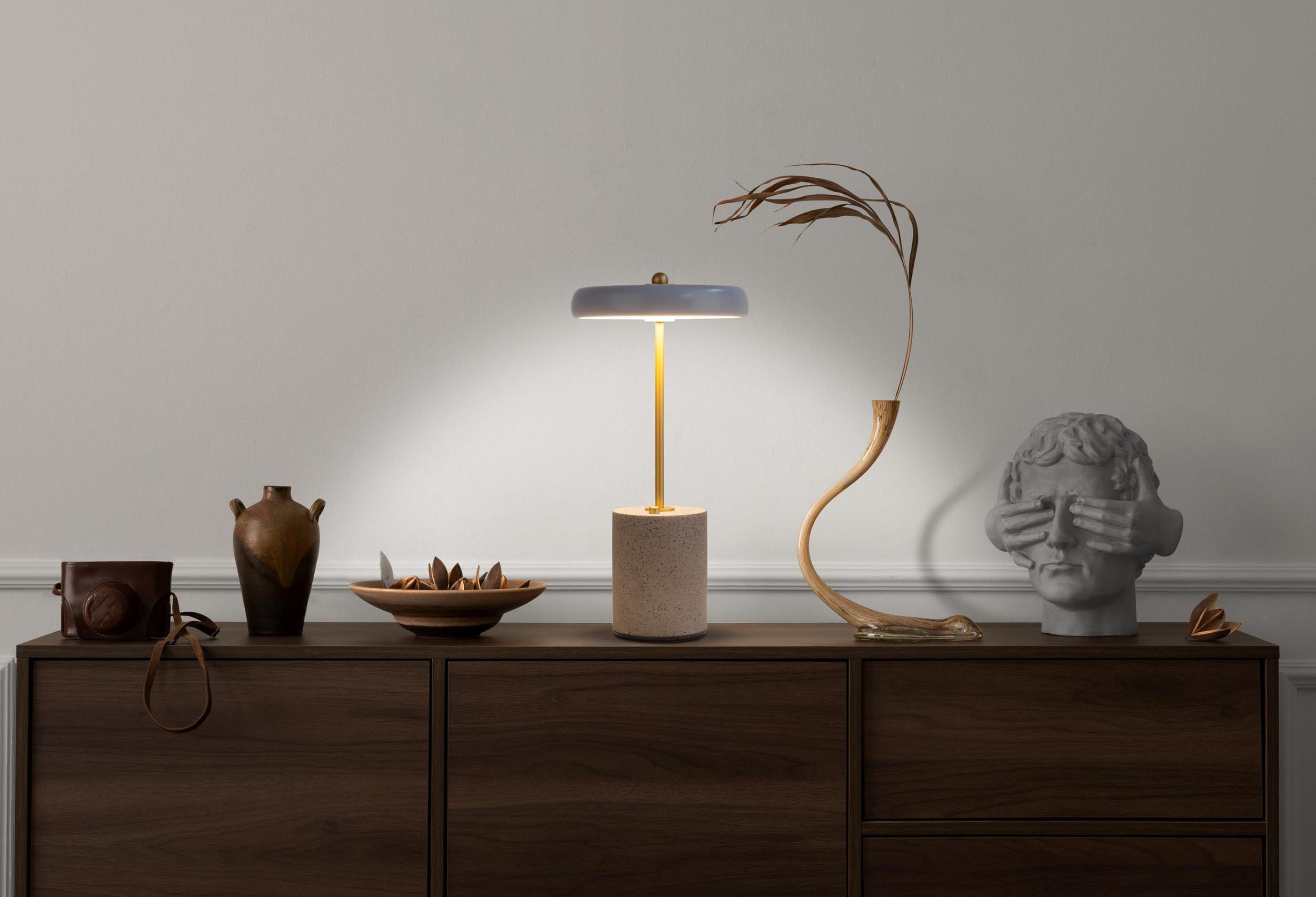 Eine Vitrine mit Lampe, Vase und Büste.