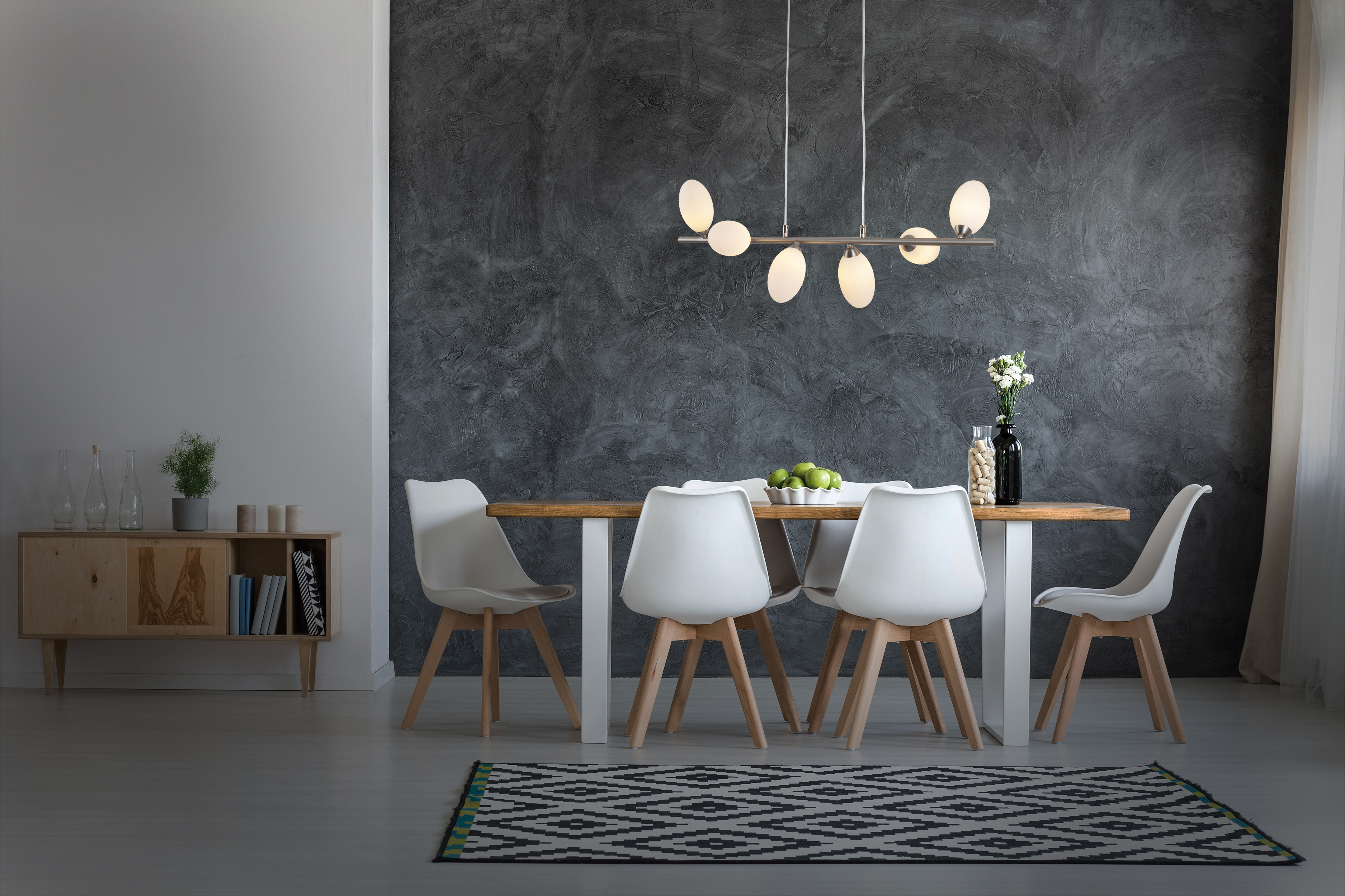 Esszimmer mit Holztisch, weißen Stühlen, einem Teppich und einer Hängeleuchte.