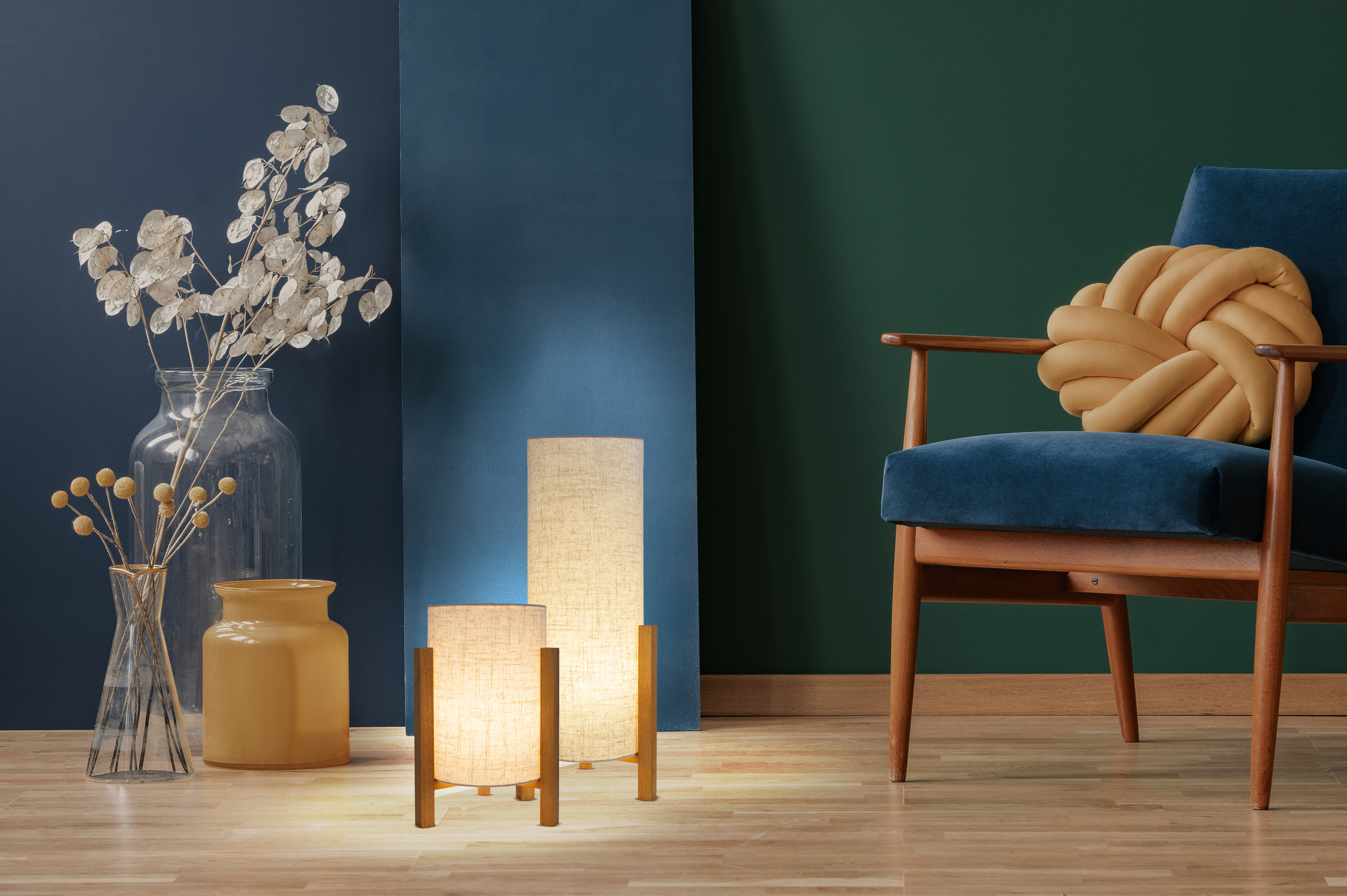 Zwei Lampen mit Holzständern, Pflanzen in Vasen und ein blauer Sessel.