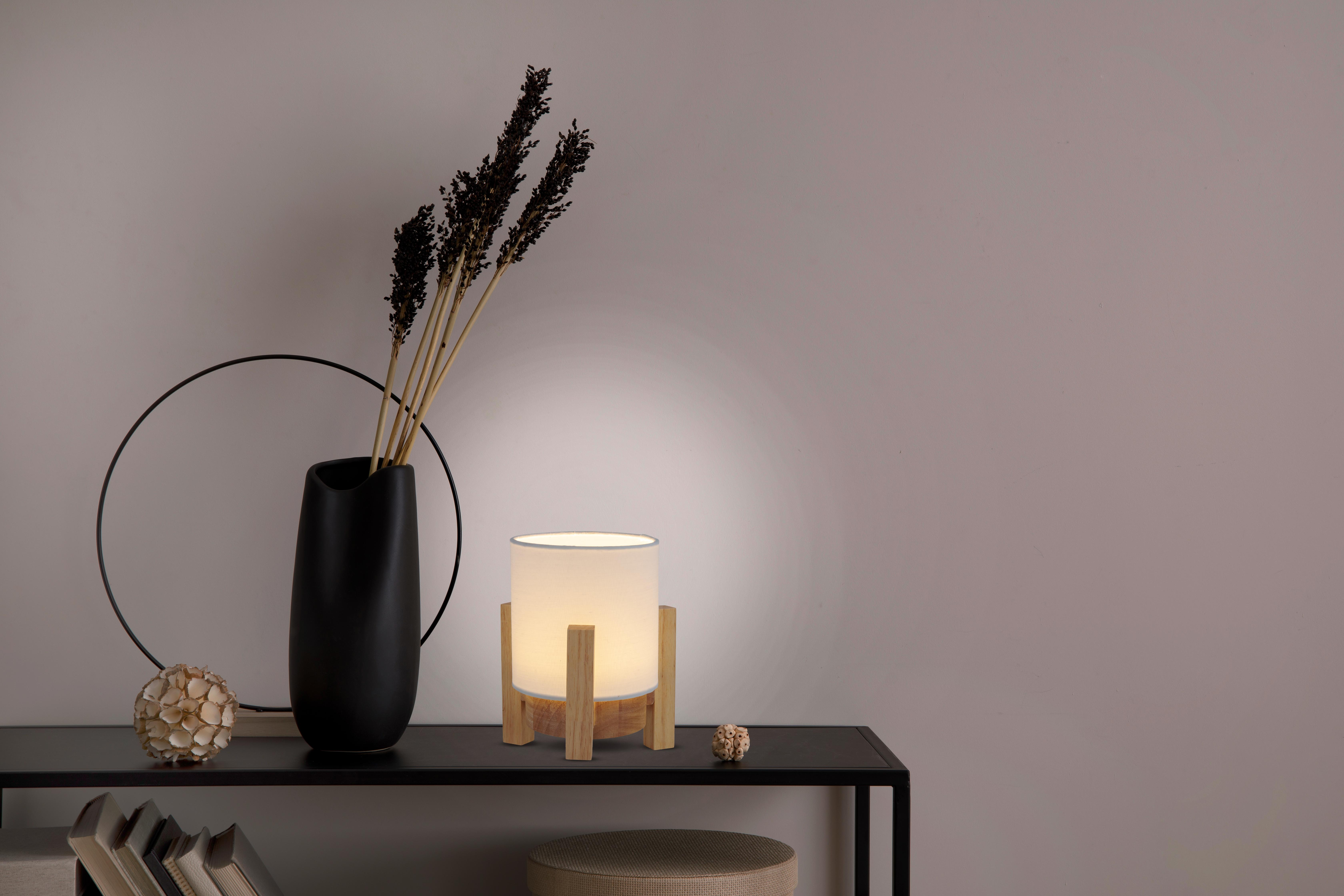 Tisch mit schwarzer Vase mit getrockneten Stielen, einer Lampe und einem dekorativen Ball.