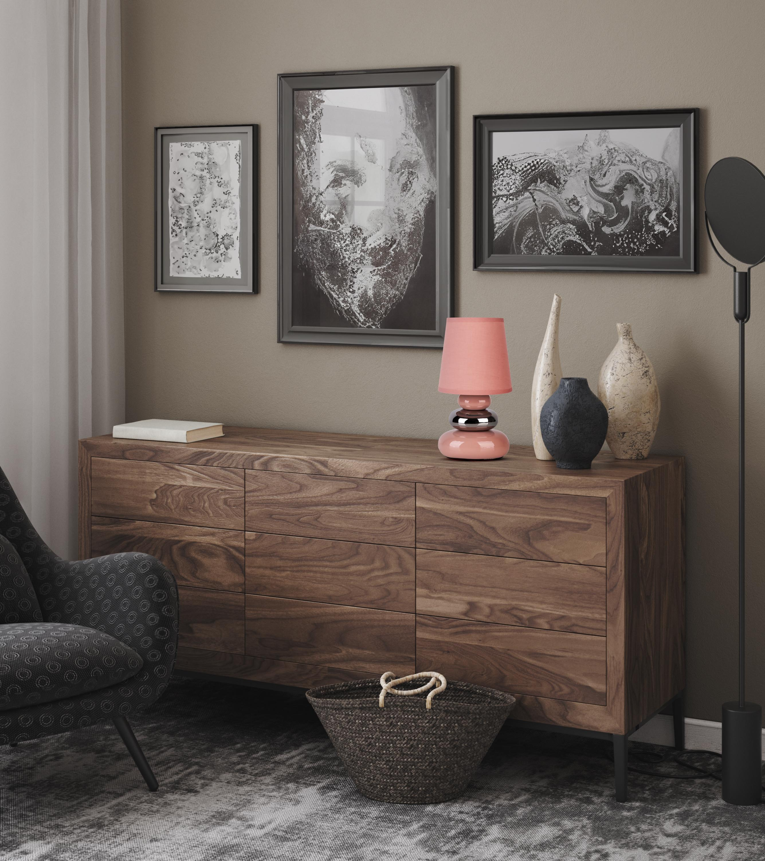 Ein Holzschrank mit gerahmter Kunst, einer Lampe und Vasen. In der linken Ecke steht ein Stuhl.