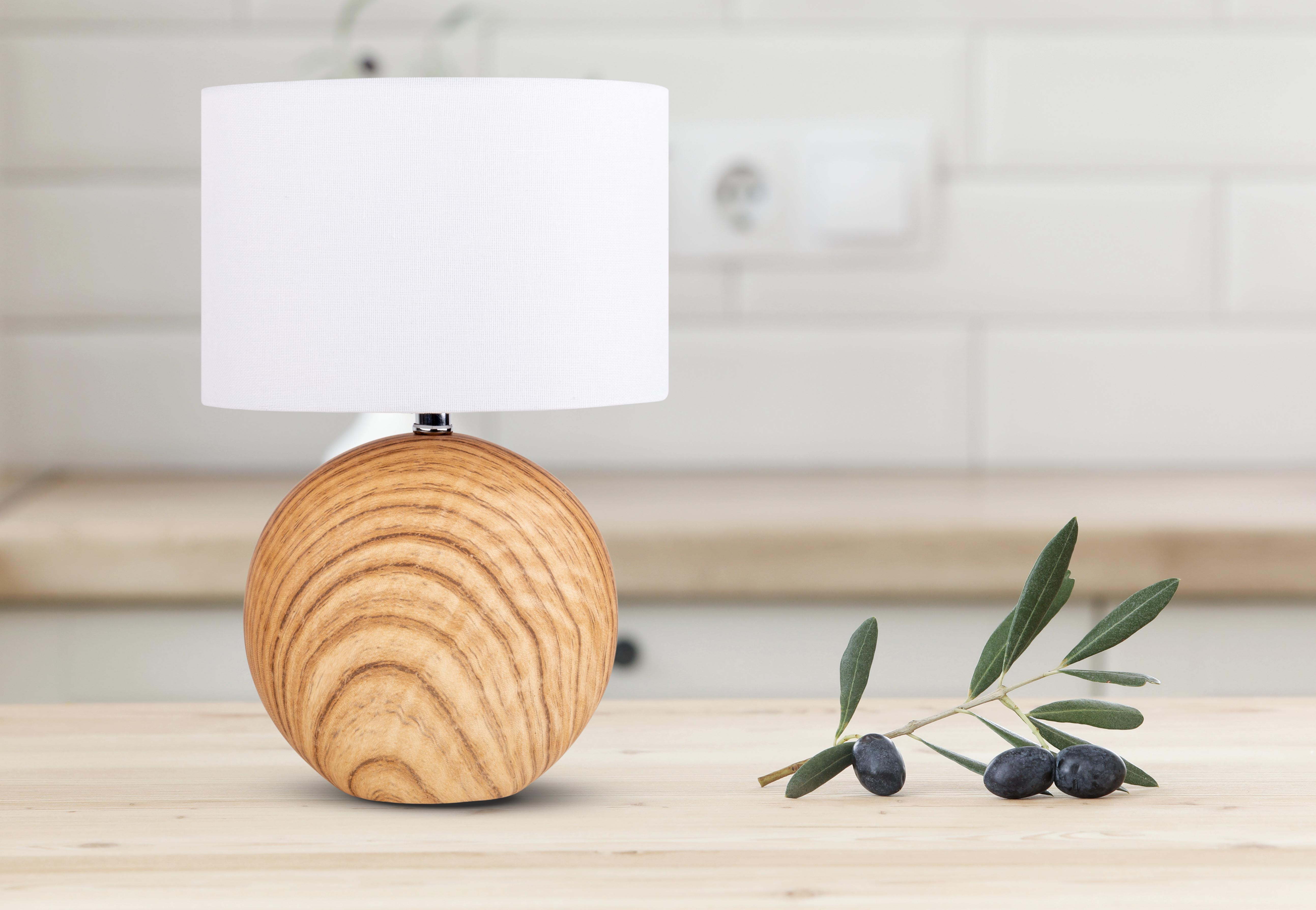 Eine Tischlampe aus Holz mit weißem Lampenschirm, Oliven und Zweig.