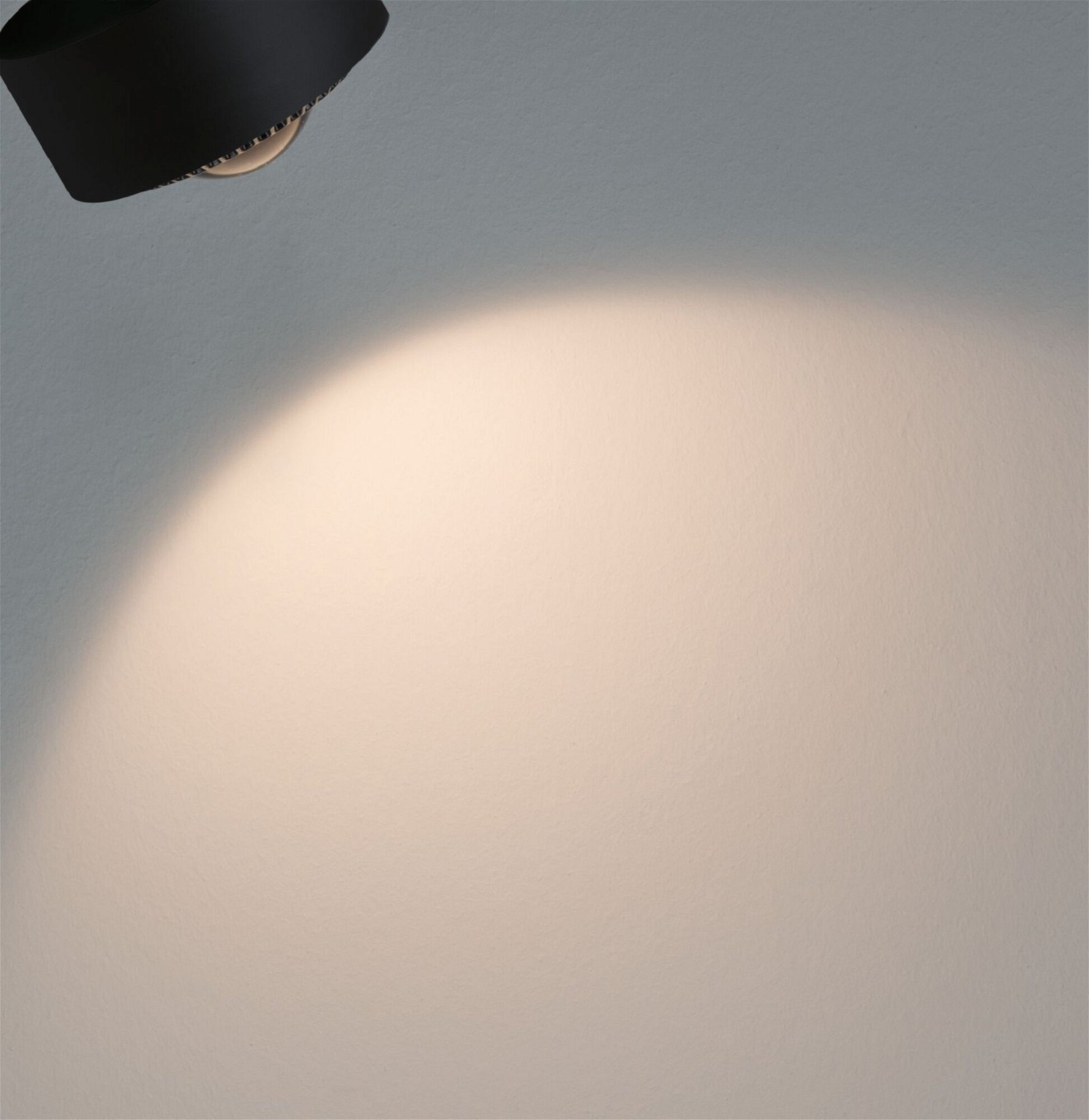 Ein Scheinwerfer, der auf eine weiße Wand scheint. Das Licht ist hell und fokussiert.