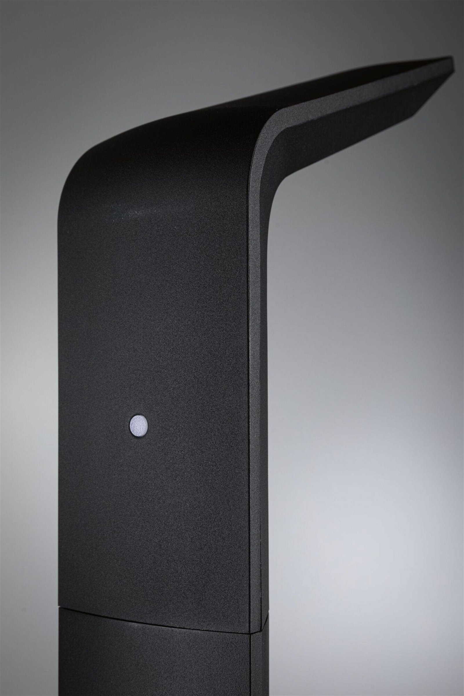 Czarna, nowoczesna lampa z zakrzywioną górą. Mała kropka światła znajduje się z boku.