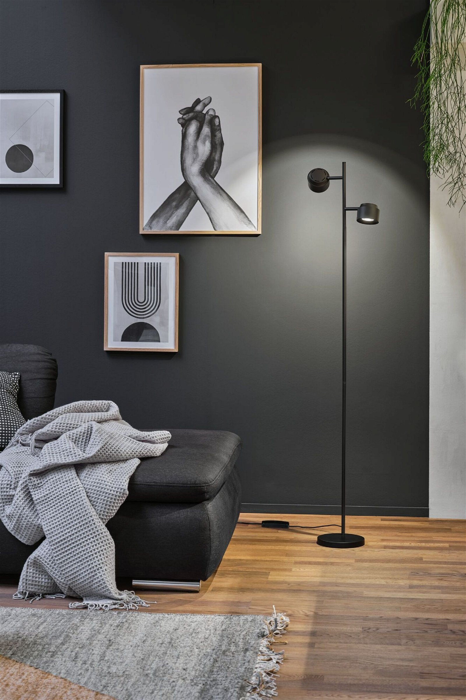 Wohnzimmerszene mit Stehlampe, Kunstdrucken und Sofa.