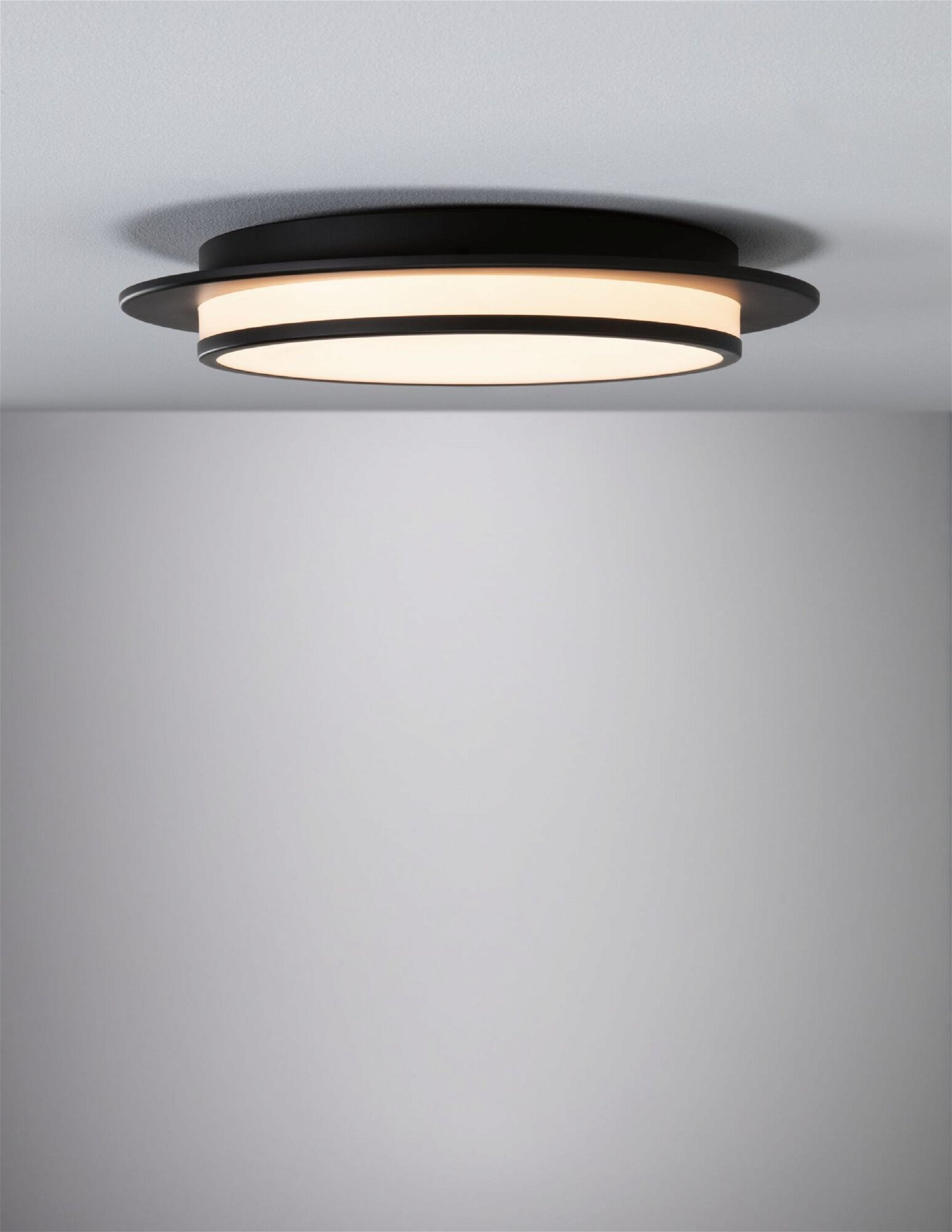 Runde schwarze Deckenleuchte mit zwei konzentrischen Kreisen, die Licht emittieren.