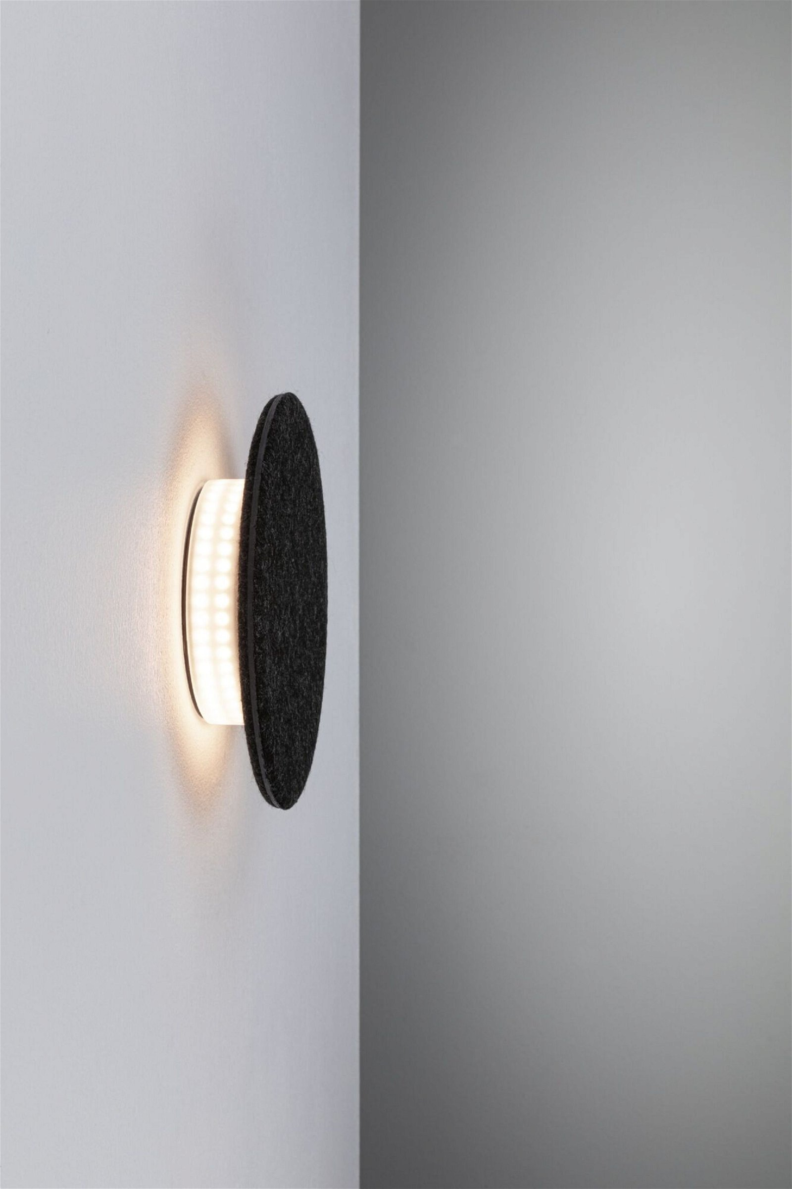 Eine wandmontierte schwarze kreisförmige Leuchte mit weißem Licht.