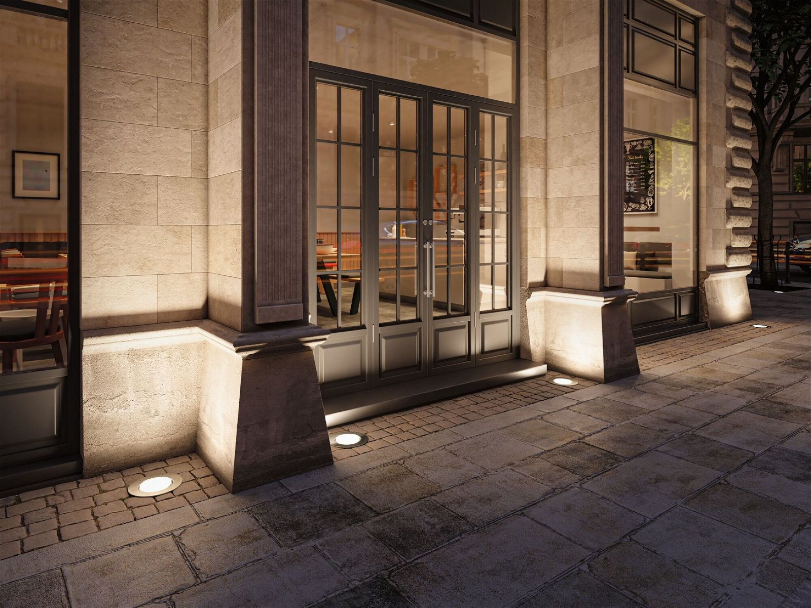 Fasada budynku z dużymi szklanymi drzwiami. Oświetlenie podłogowe oświetla bruk.