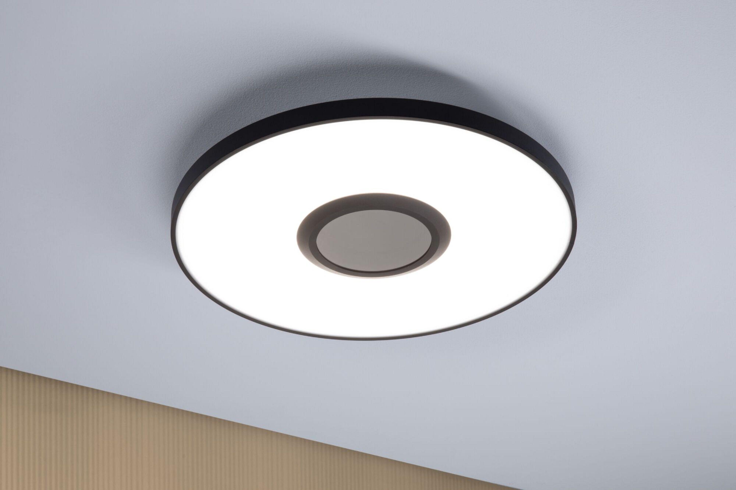 Eine weiße und schwarze Deckenlampe. Die Lampe ist eingeschaltet.