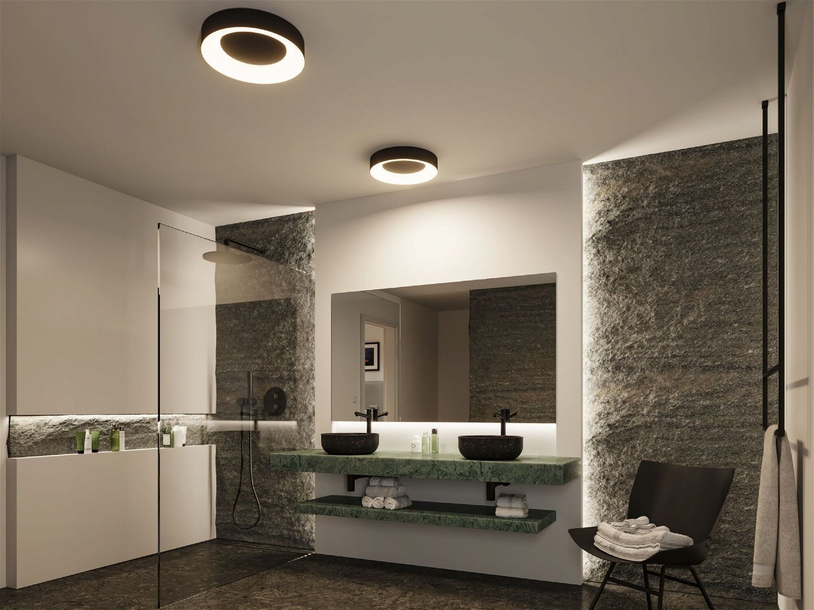 Modernes Badezimmer. Zwei schwarze Waschbecken, großer Spiegel und zwei runde Lichter. Grüne Akzente.