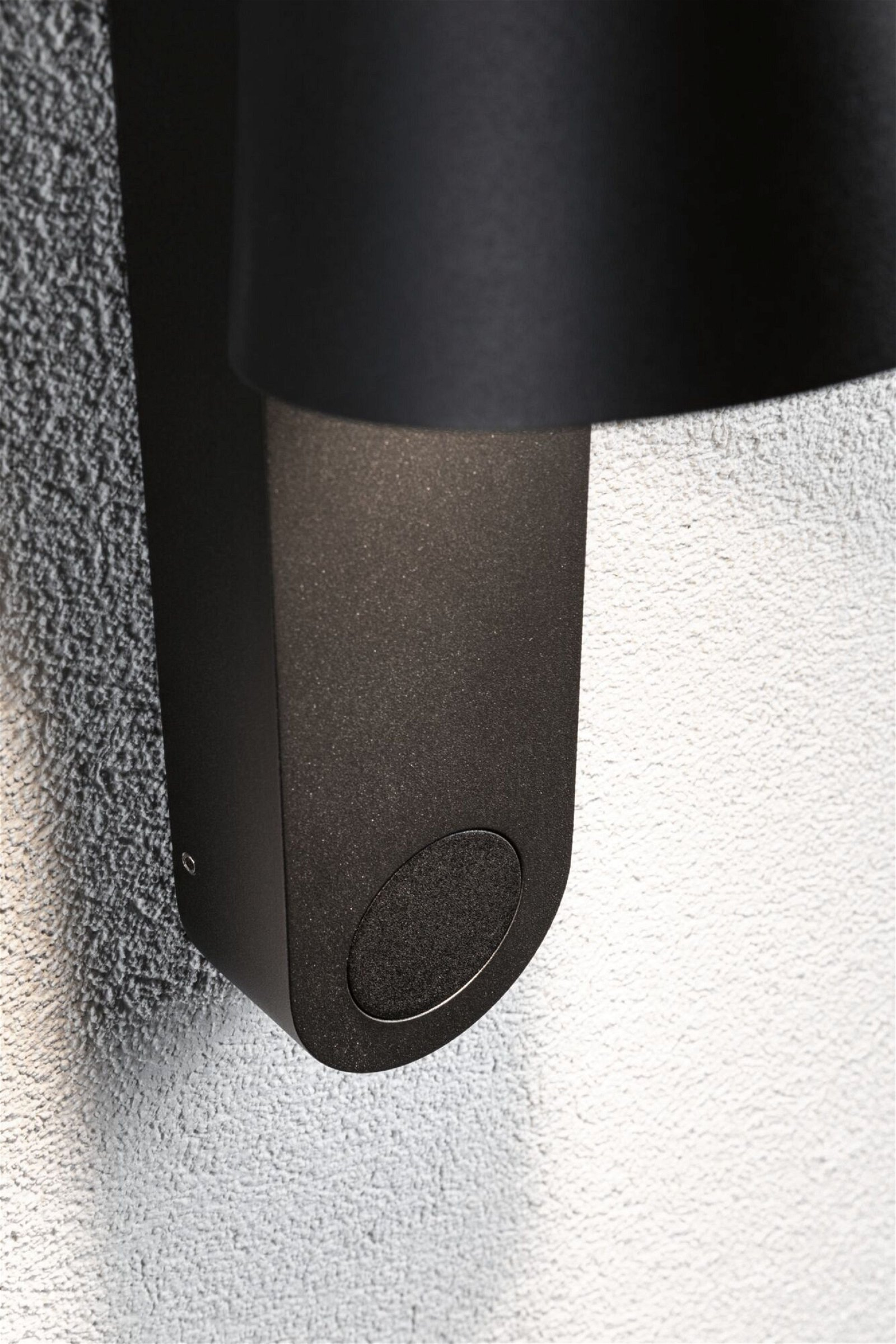 Czarna lampa ścienna zewnętrzna zamontowana na teksturowanej białej ścianie.