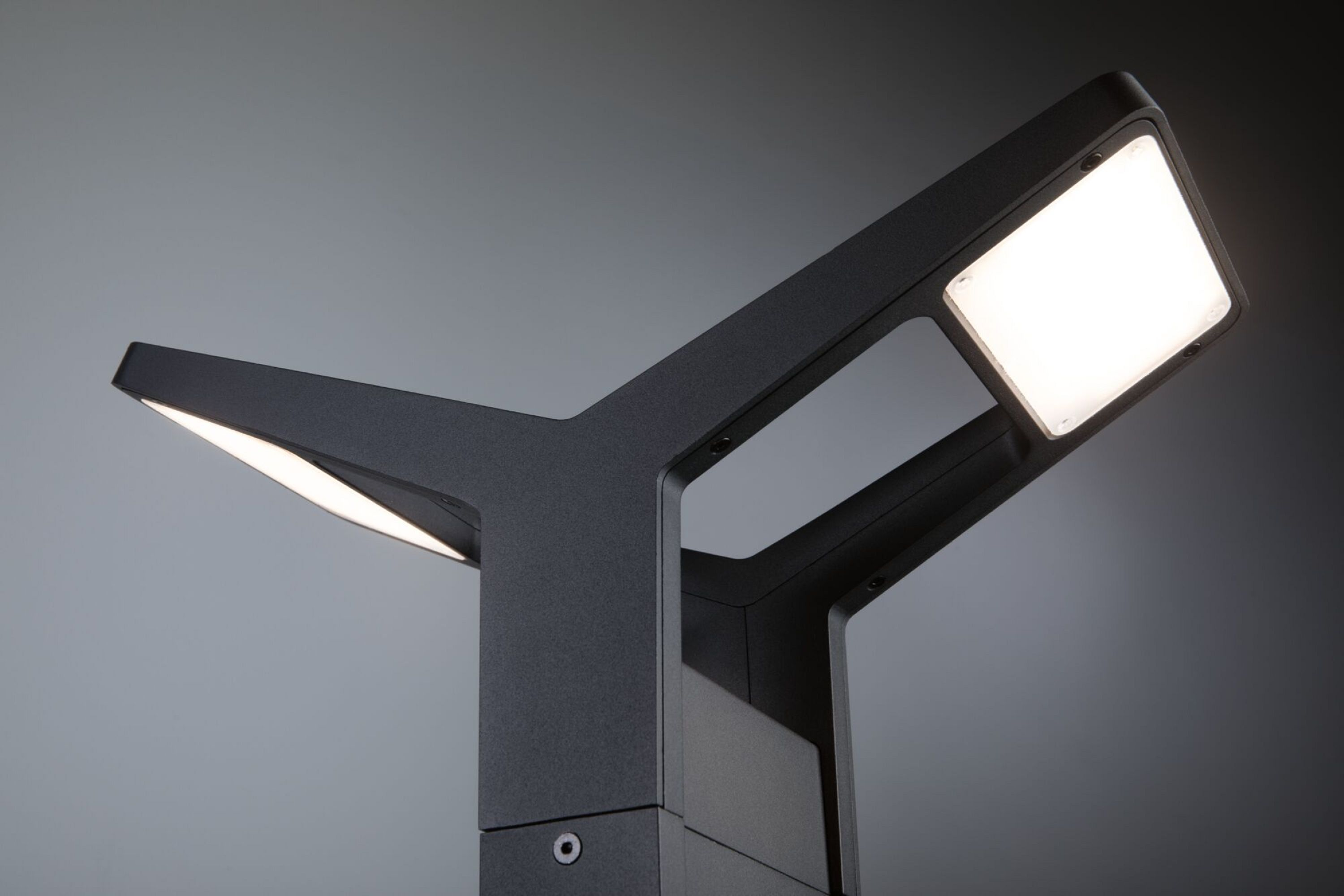 Nowoczesna ciemnoszara lampa zewnętrzna z dwoma białymi światłami na szarym tle.