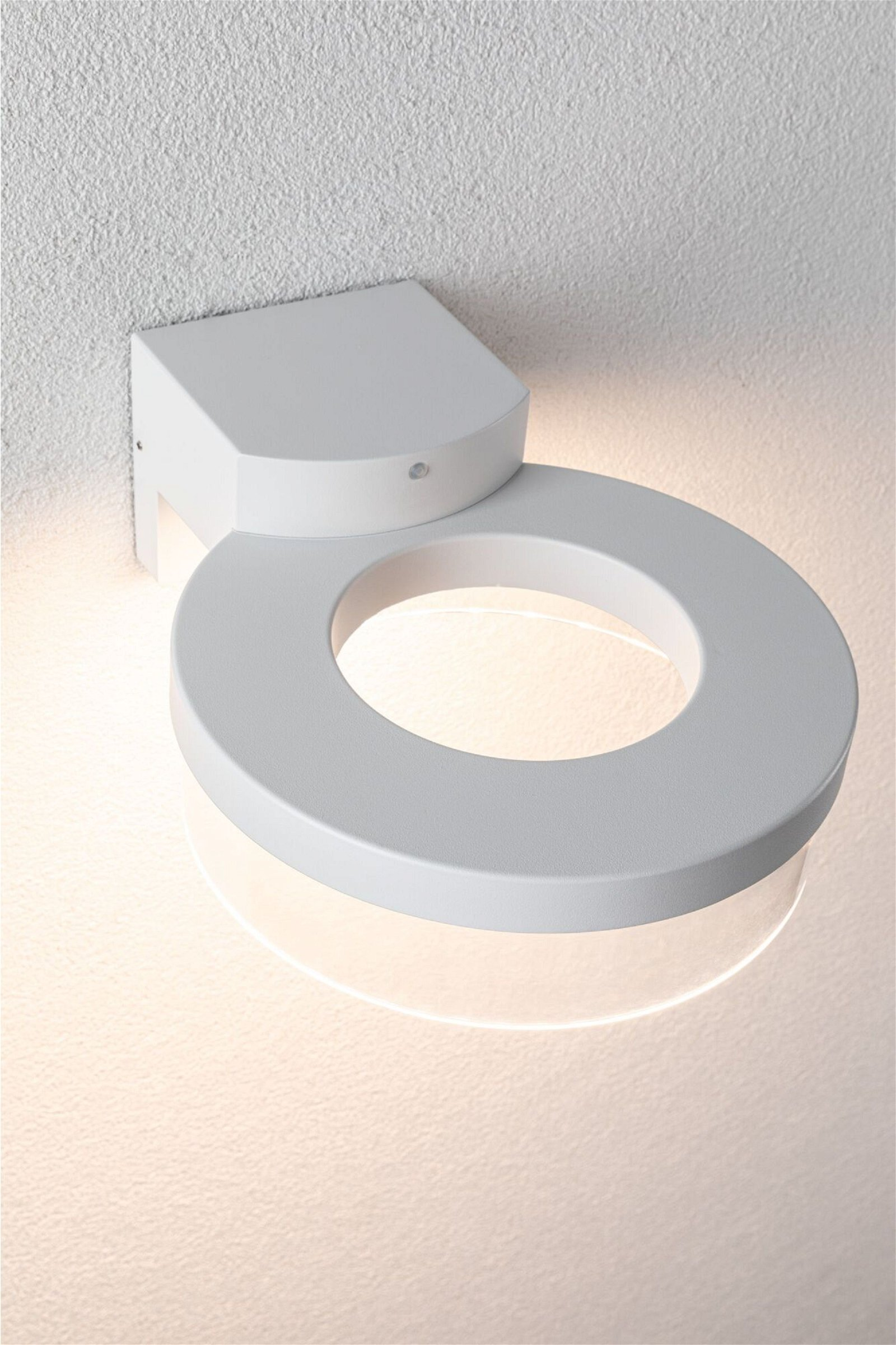 Biała lampa ścienna o okrągłym kształcie, emitująca światło.