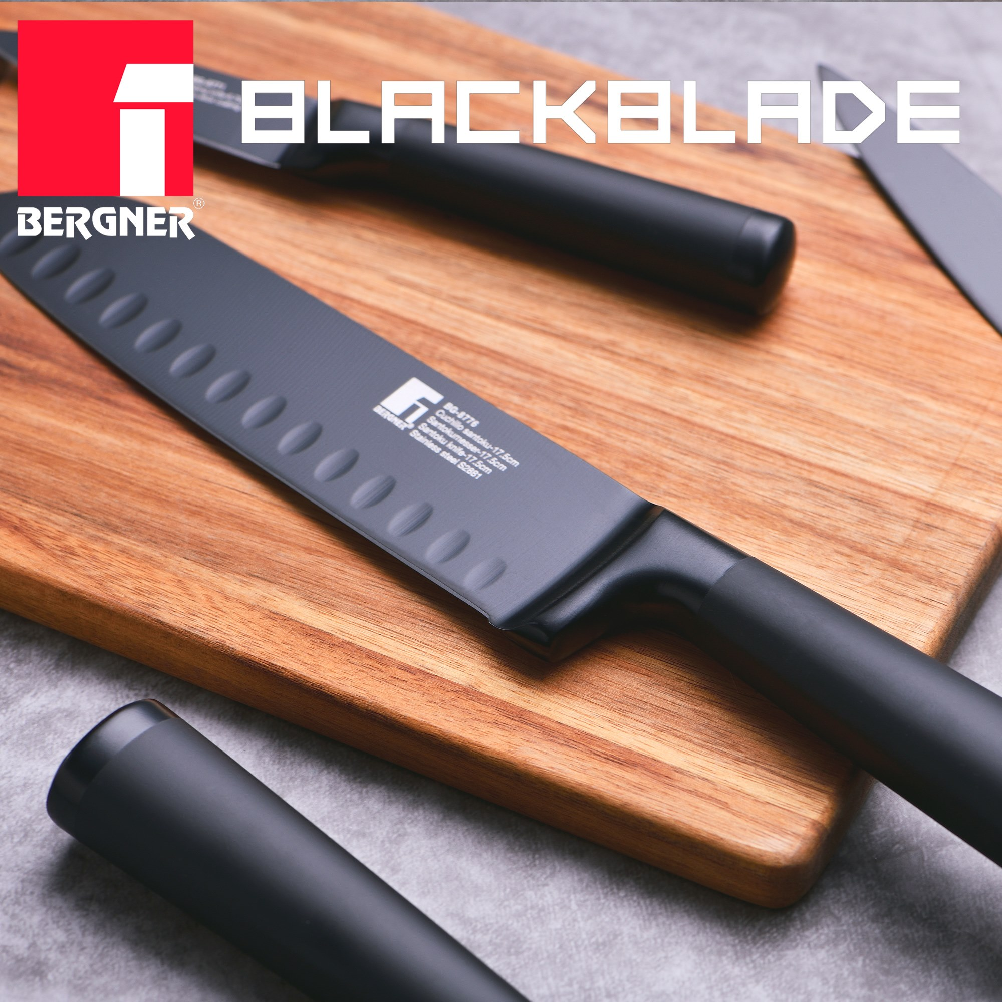 Un cuchillo negro sobre una tabla de cortar de madera. Se ven otros cuchillos y el texto 'BLACKBLADE'.