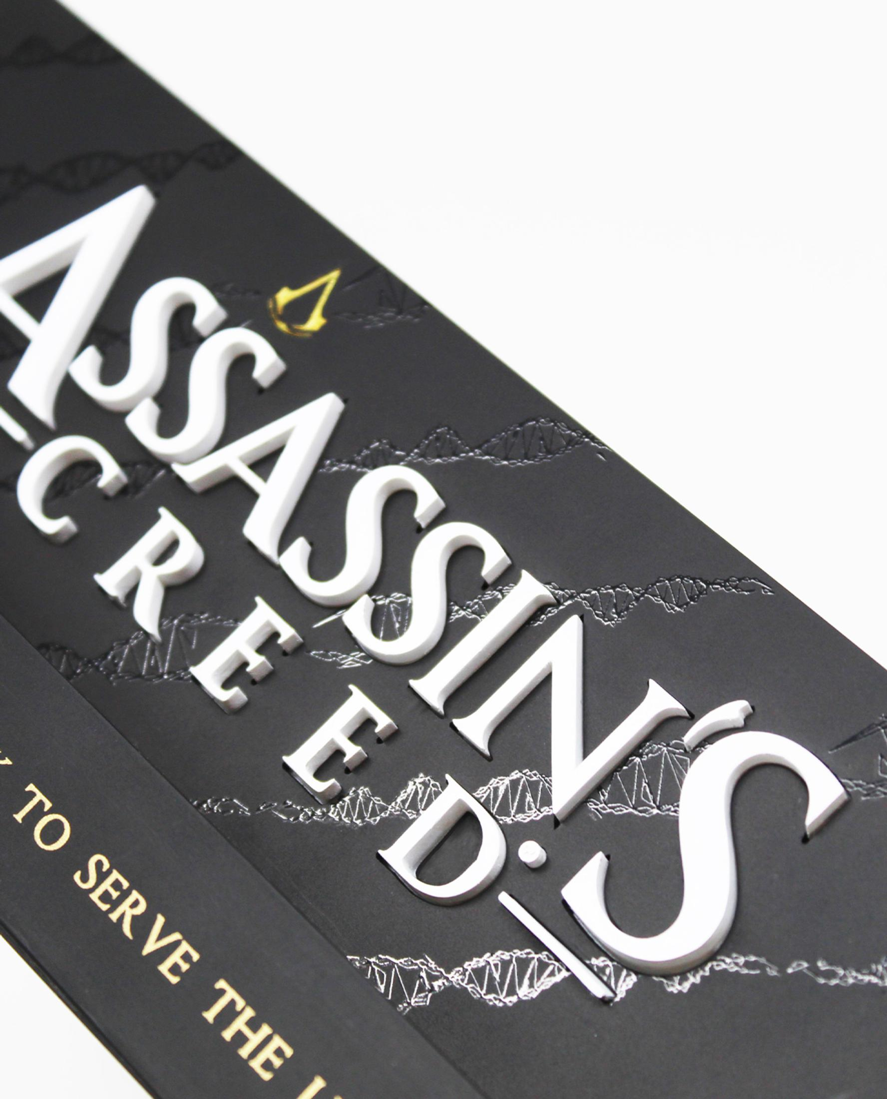Nahaufnahme des Buchcovers von 'Assassin's Creed' mit weißem, erhabenen Schriftzug.