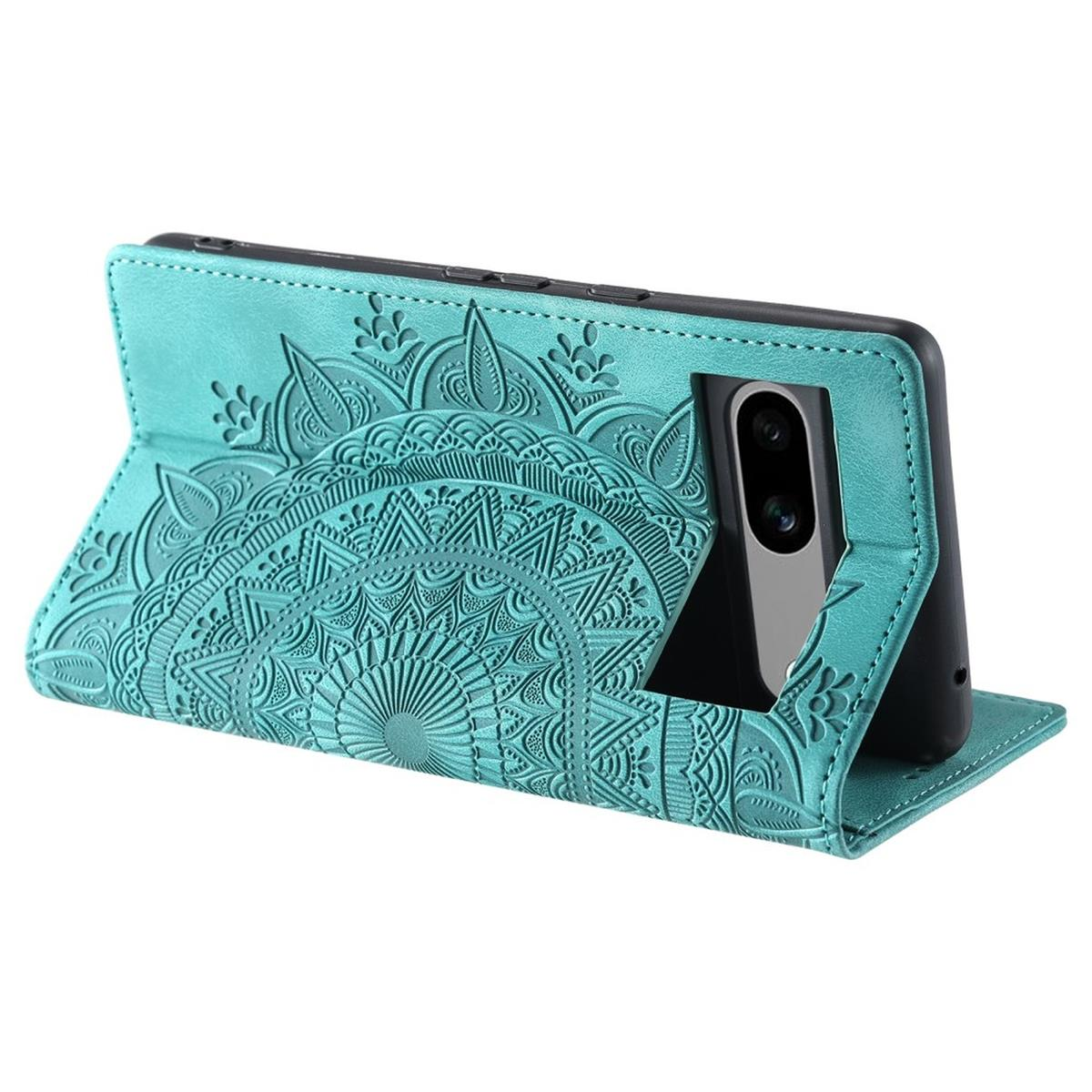 Türkisfarbene Handyhülle mit Mandala-Design, geöffnet, und Telefon sichtbar. Mit strukturiertem Muster. Weißer Hintergrund.