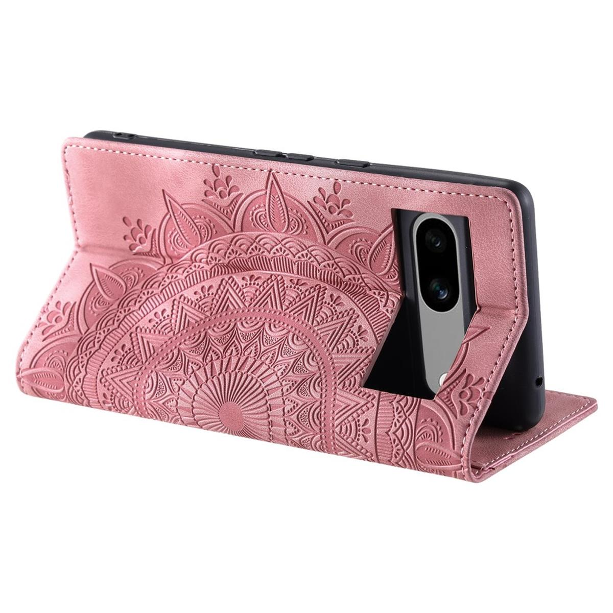 Rosa Handyhülle mit Mandala-Design, hält ein Handy. Das Handy ist schwarz, die Hülle ist offen.