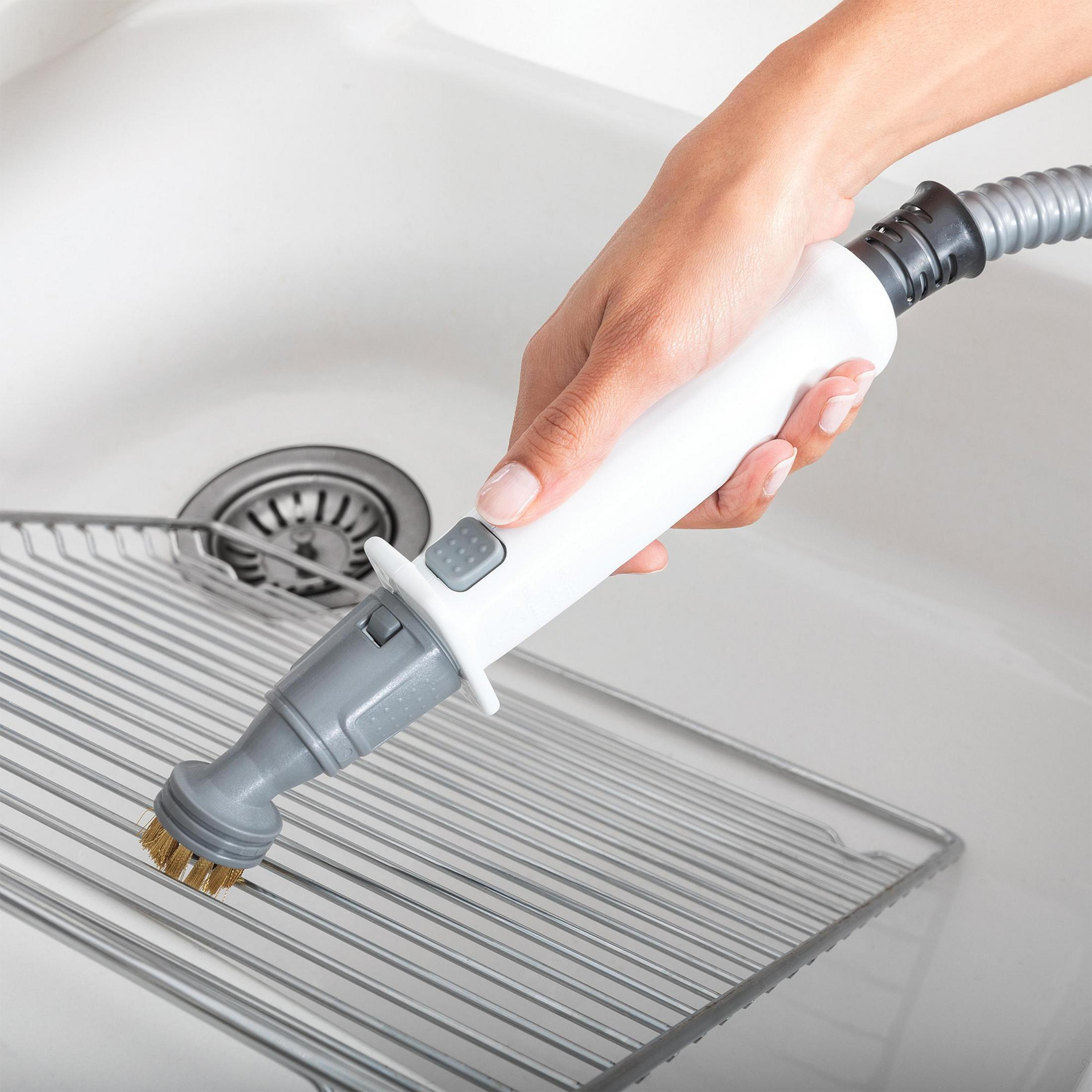 Ręka używająca szczotki do czyszczenia na metalowym ruszcie w zlewie, biała rączka.