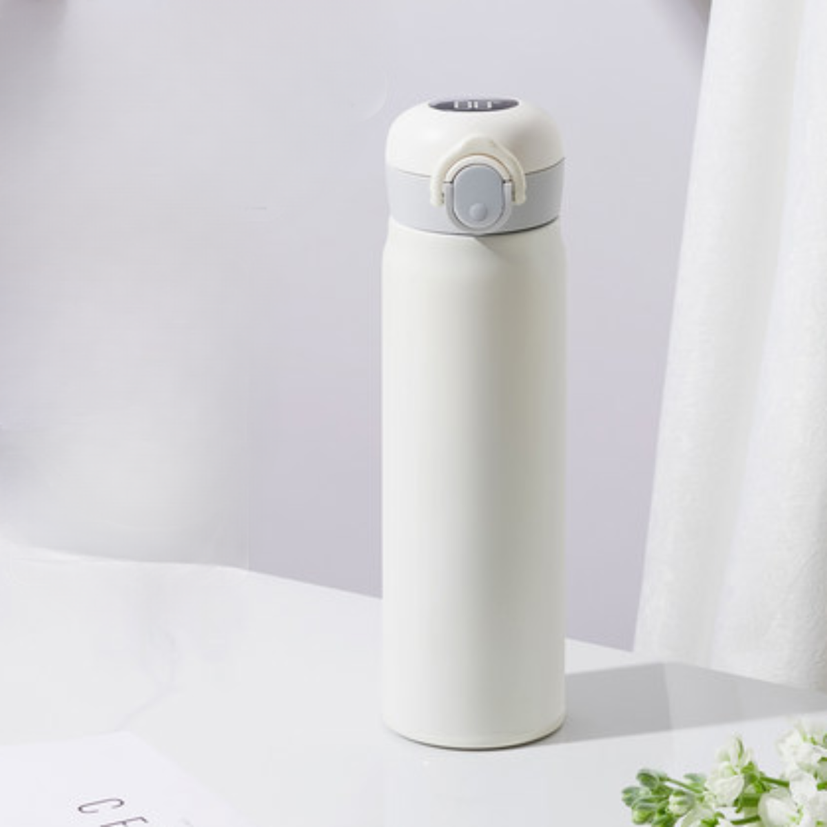 Eine weiße, isolierte Wasserflasche mit grauem Deckel auf weißer Oberfläche.