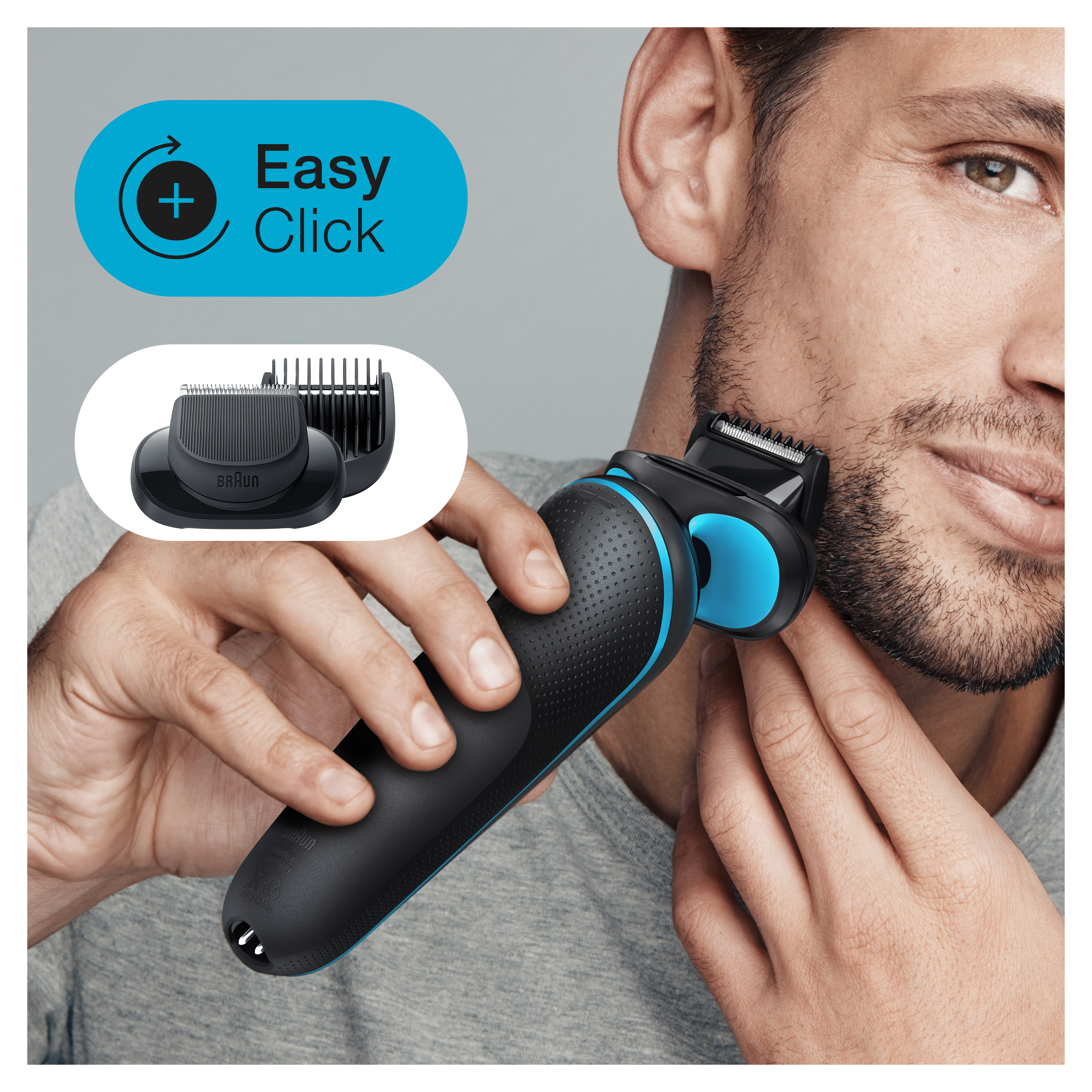 Mann rasiert sich mit einem schwarz-blauen Elektrorasierer, neben einem Trimmeraufsatz, auf Grau.