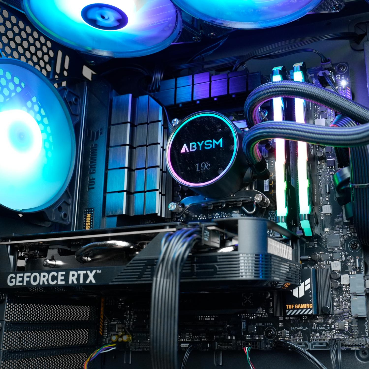 Dentro de una caja de PC: GPU, enfriador de CPU, ventiladores con luces azules y moradas. Logotipo ABYSM visible.