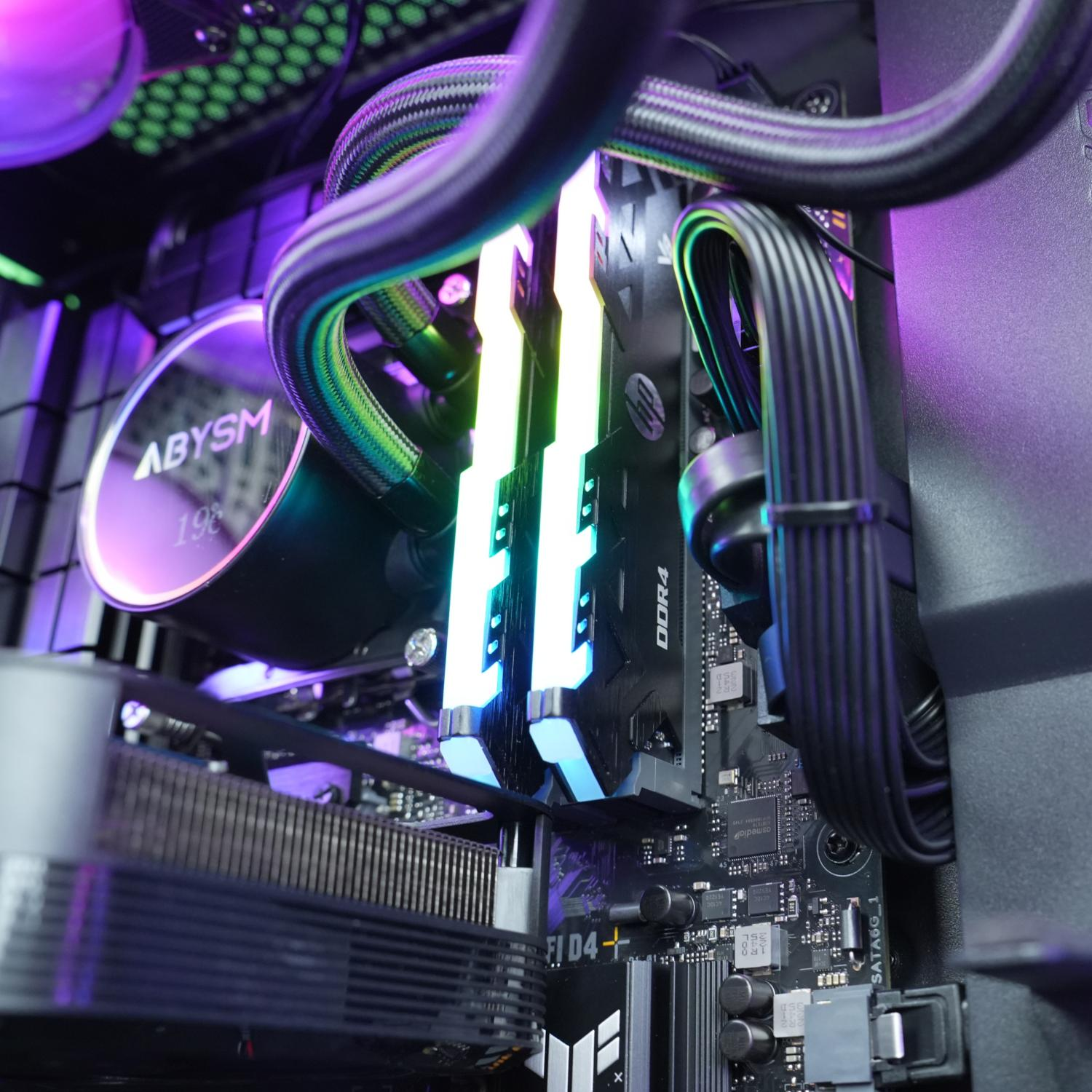 Primer plano de componentes de PC, incluyendo módulos RAM, un enfriador de agua y otras partes internas.