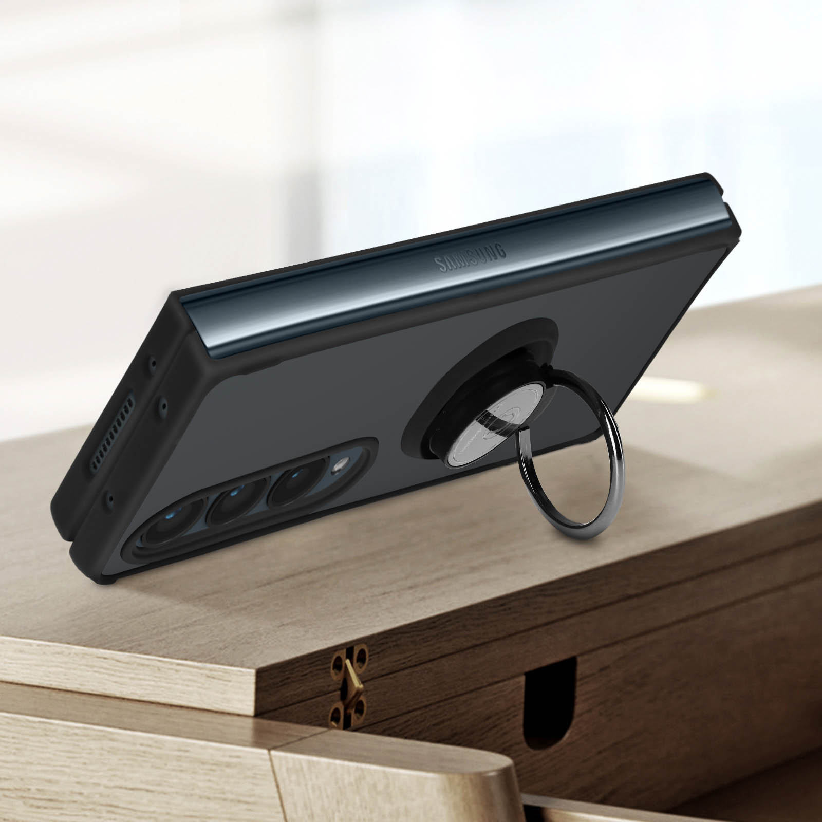 Un telefono nero è su un tavolo di legno. Ha un portanello. Lo sfondo è sfocato.