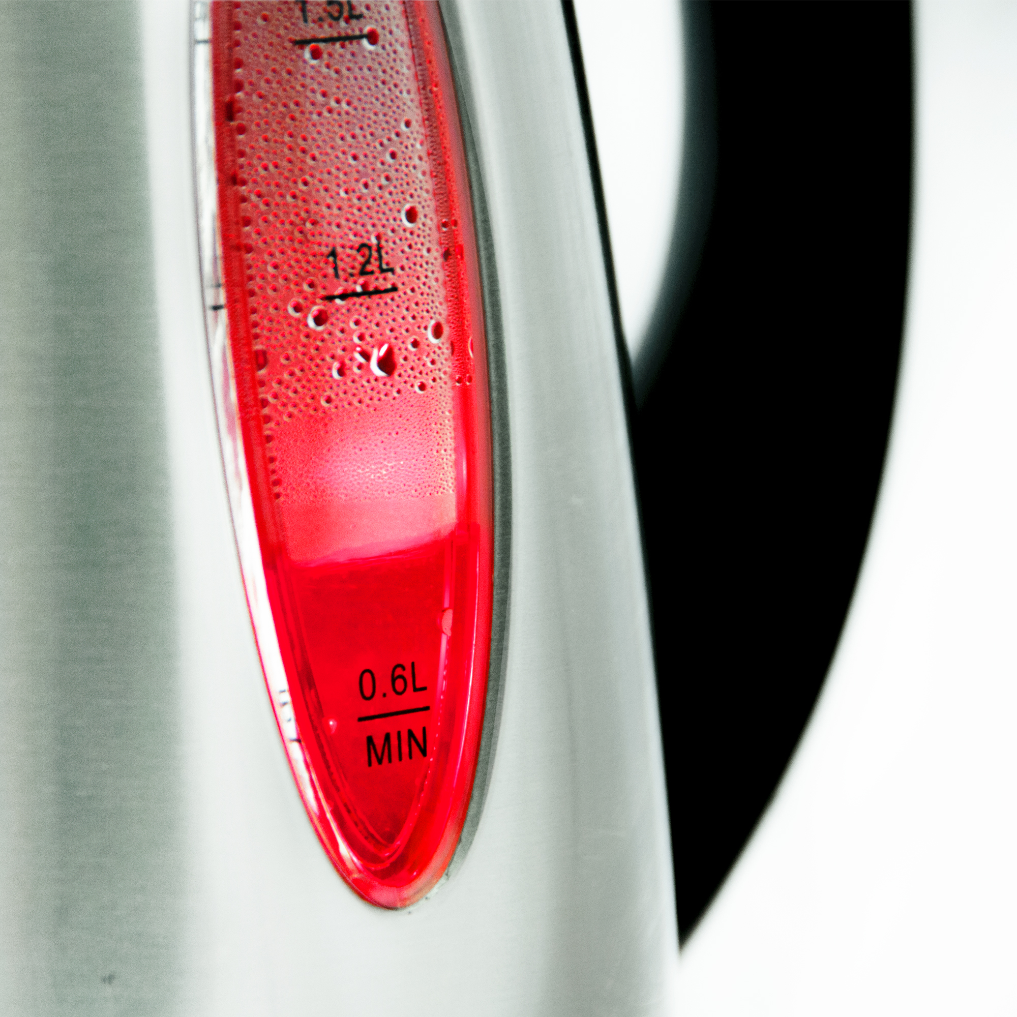 Primer plano del indicador de nivel de agua de una tetera con agua iluminada en rojo.