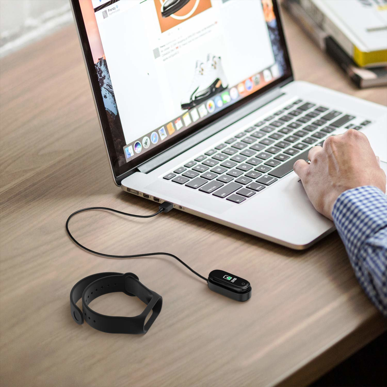 Schwarzer Fitnesstracker, der über ein USB-Kabel an einem Laptop geladen wird.