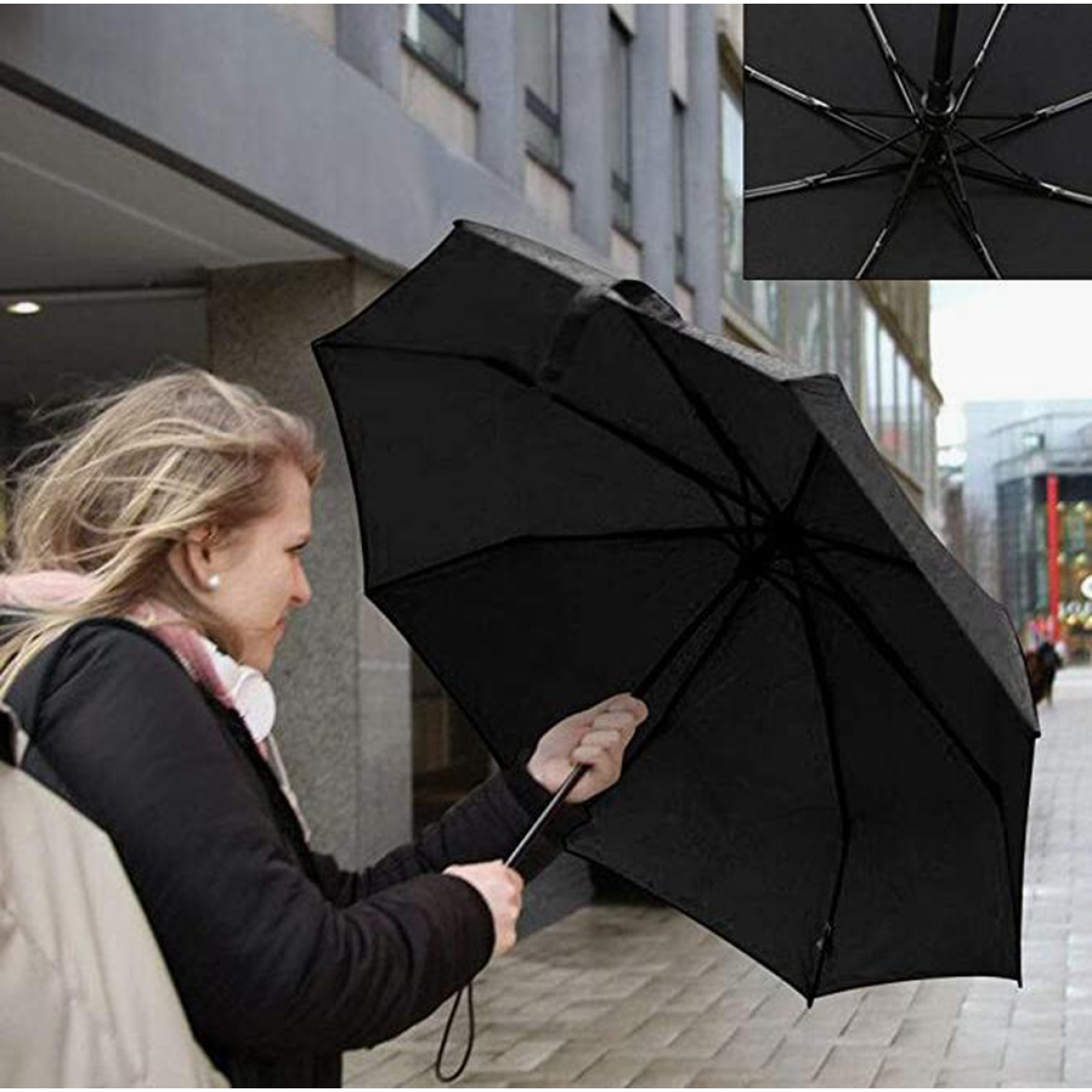 Eine Frau, die im Freien einen schwarzen Regenschirm hält.