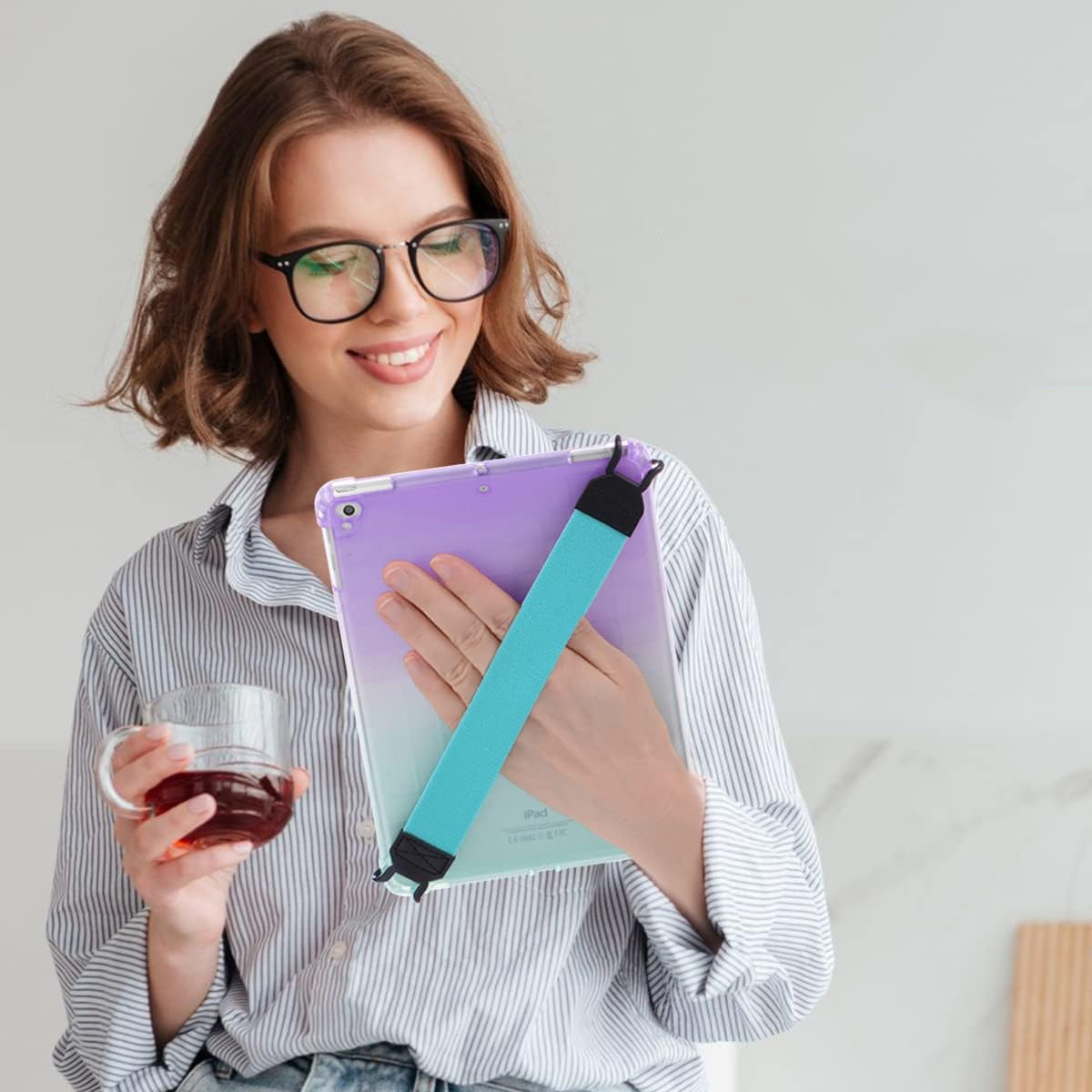 Eine Frau hält ein iPad mit Gradientenhülle und Riemen. Sie hält ein Glas Tee.