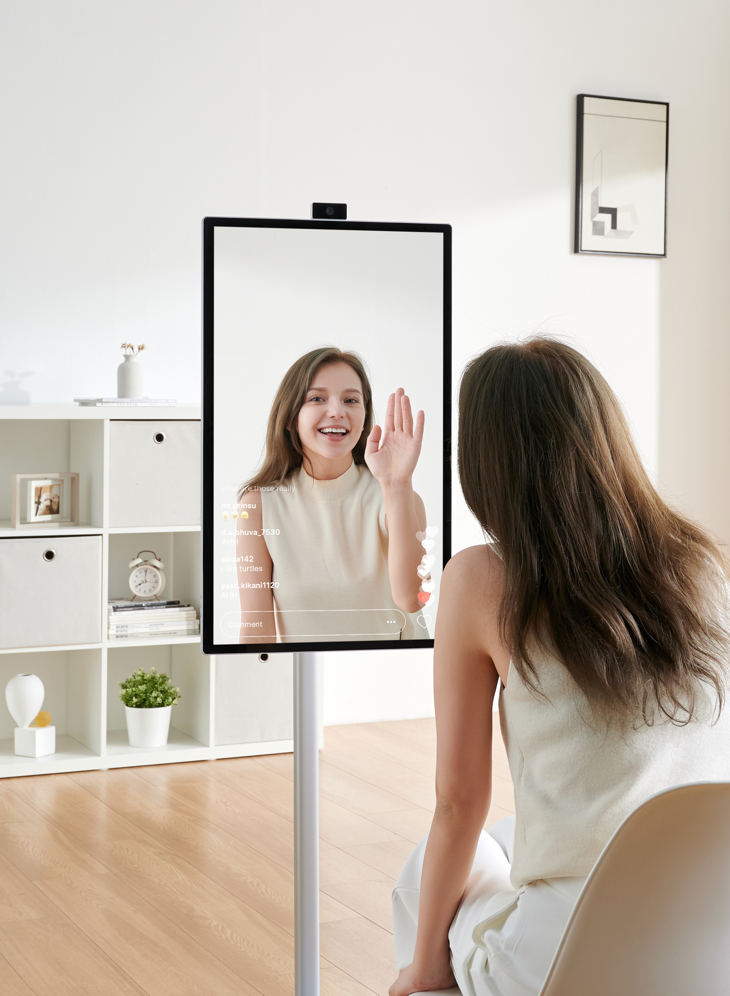 Kobieta przed lustrem macha do kamery.