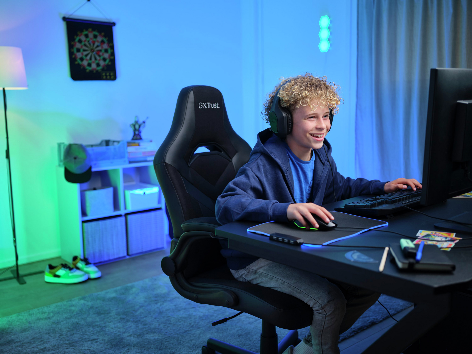 Een jongen die aan het gamen is, glimlacht naar een computerscherm en draagt een headset.