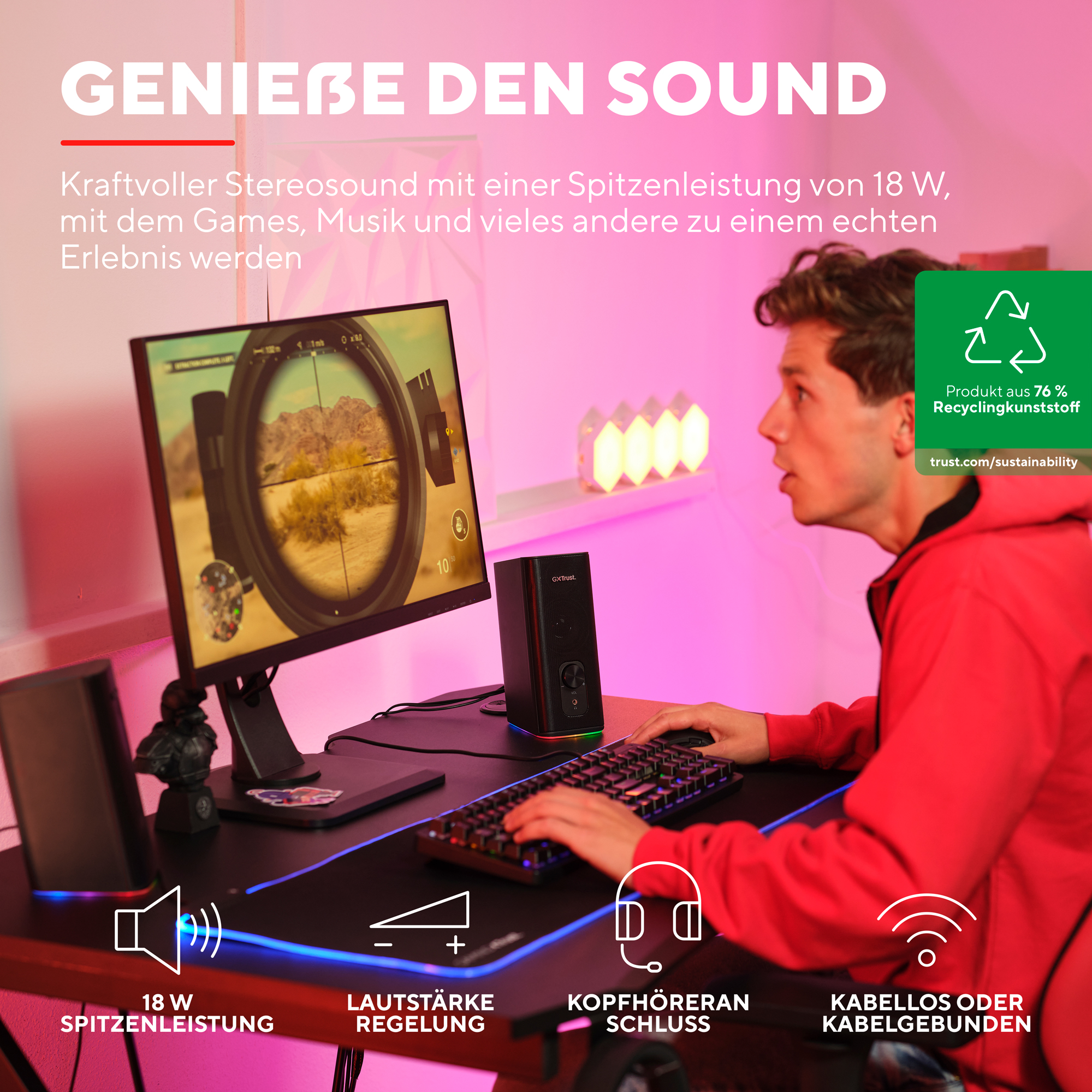 Mężczyzna grający w grę na monitorze z głośnikami, klawiaturą i zestawem słuchawkowym.