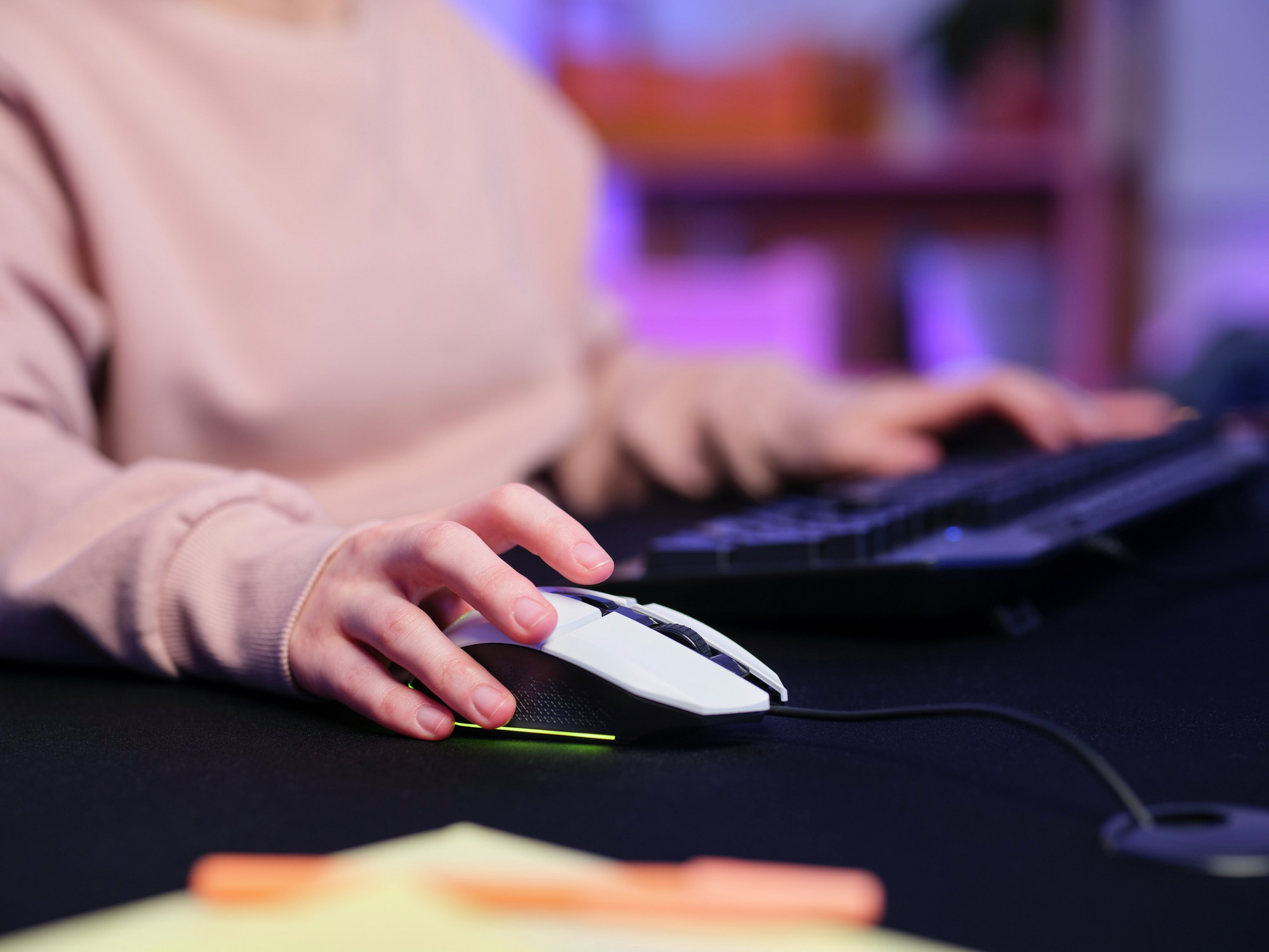 Osoba używająca białej i czarnej myszy do sterowania komputerem podczas pisania na klawiaturze.