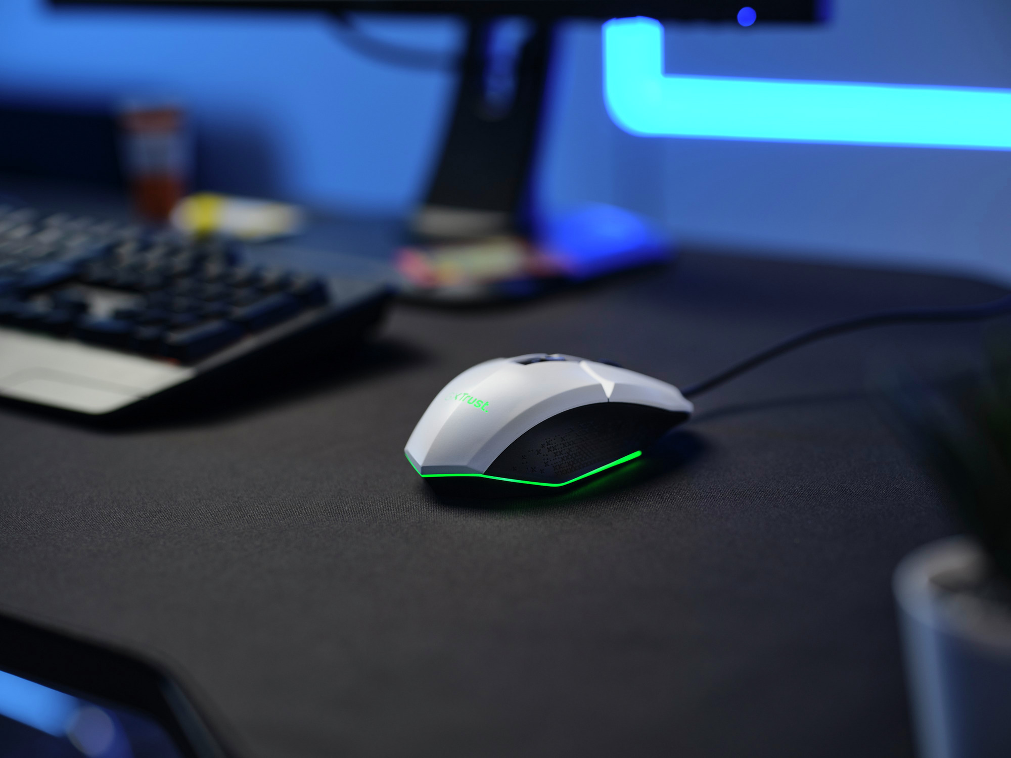 Biało-czarna mysz komputerowa z zielonym światłem, umieszczona na czarnej podkładce pod mysz.