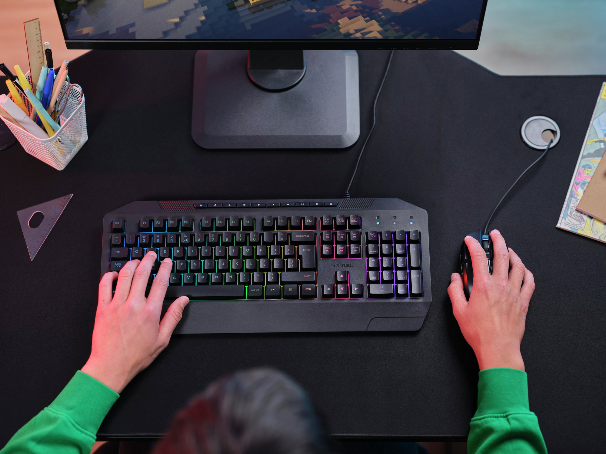 Ręce na podświetlanej, kolorowej klawiaturze i myszce do gier na czarnym biurku.