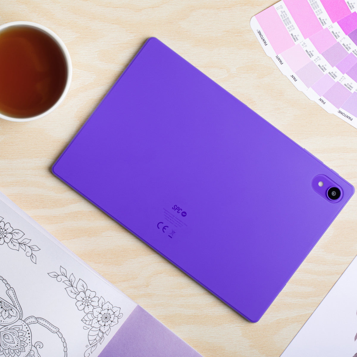 Tablet viola su un tavolo di legno. Una tazza di tè, un libro da colorare e campioni di colore.