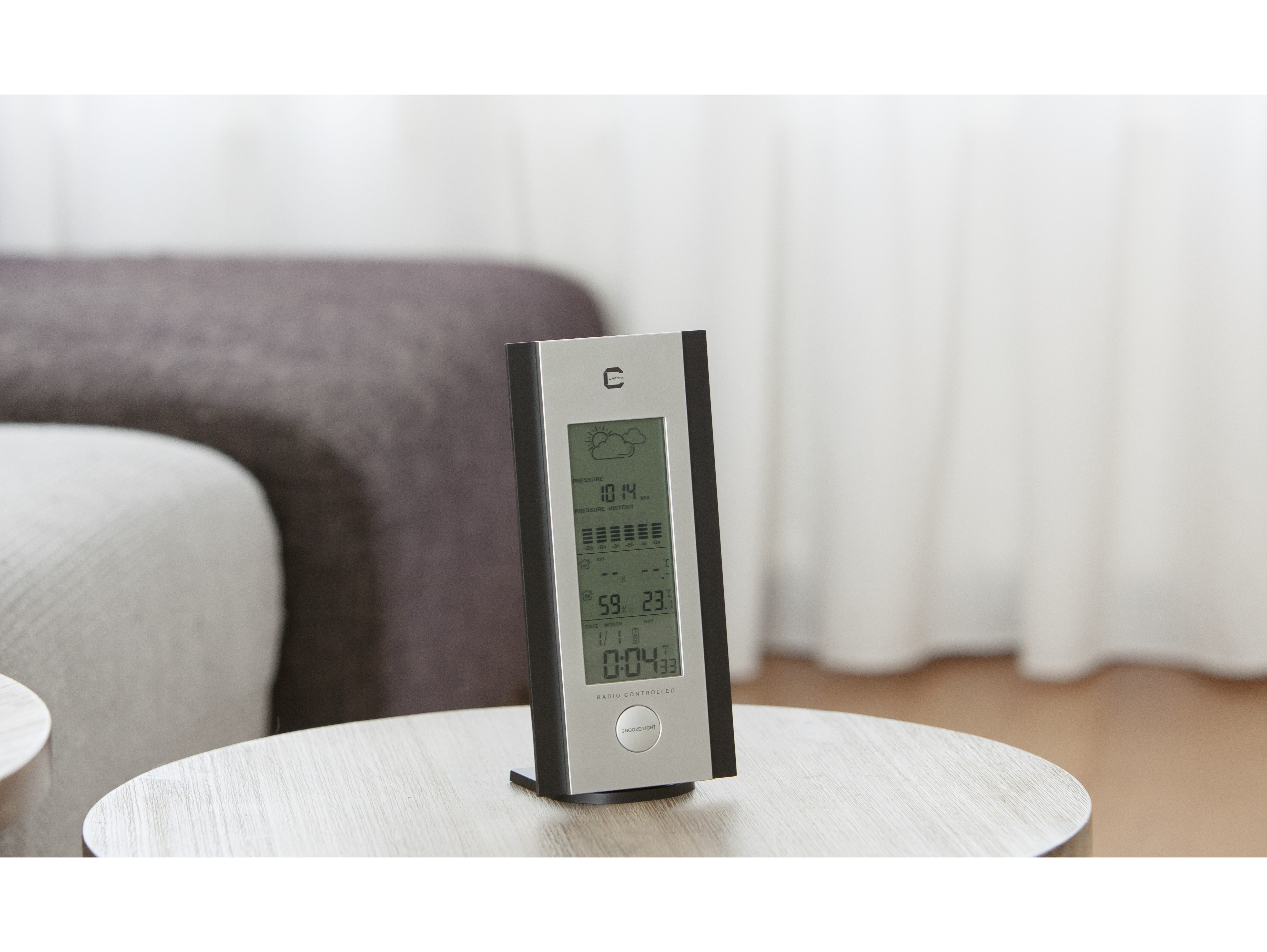 A weather station with a display showing weather info. Silver and black color.